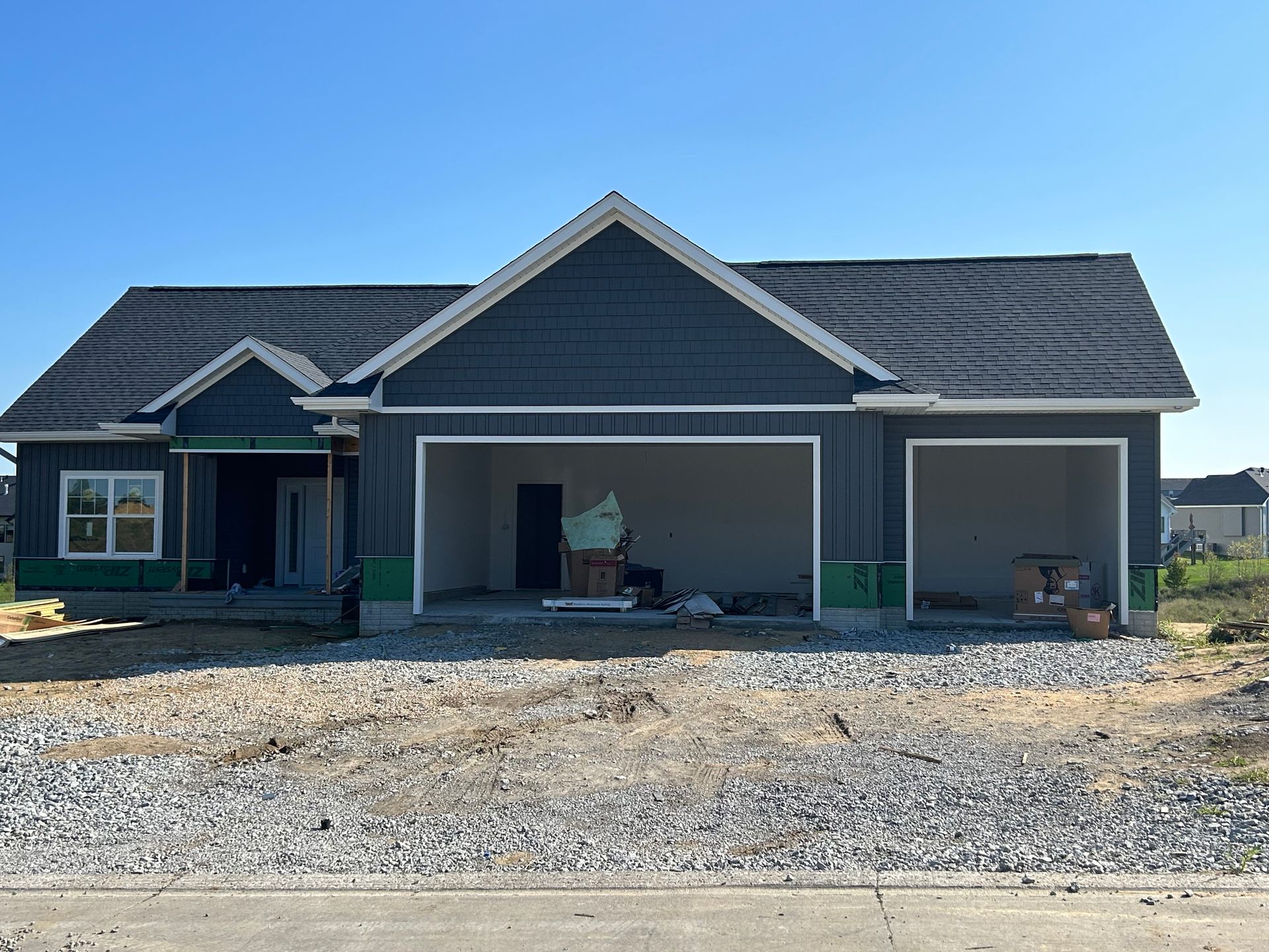 A house that is being built with a garage and a lot of gravel in front of it.