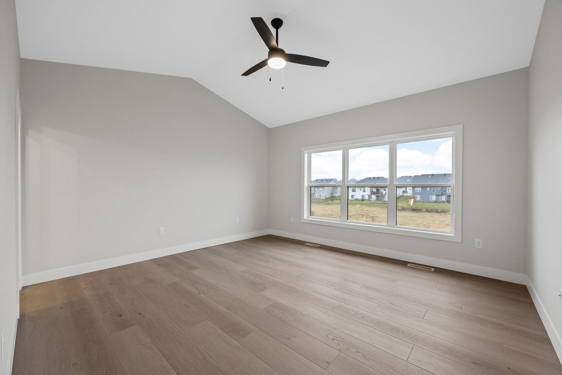 An empty room with hardwood floors and a ceiling fan.