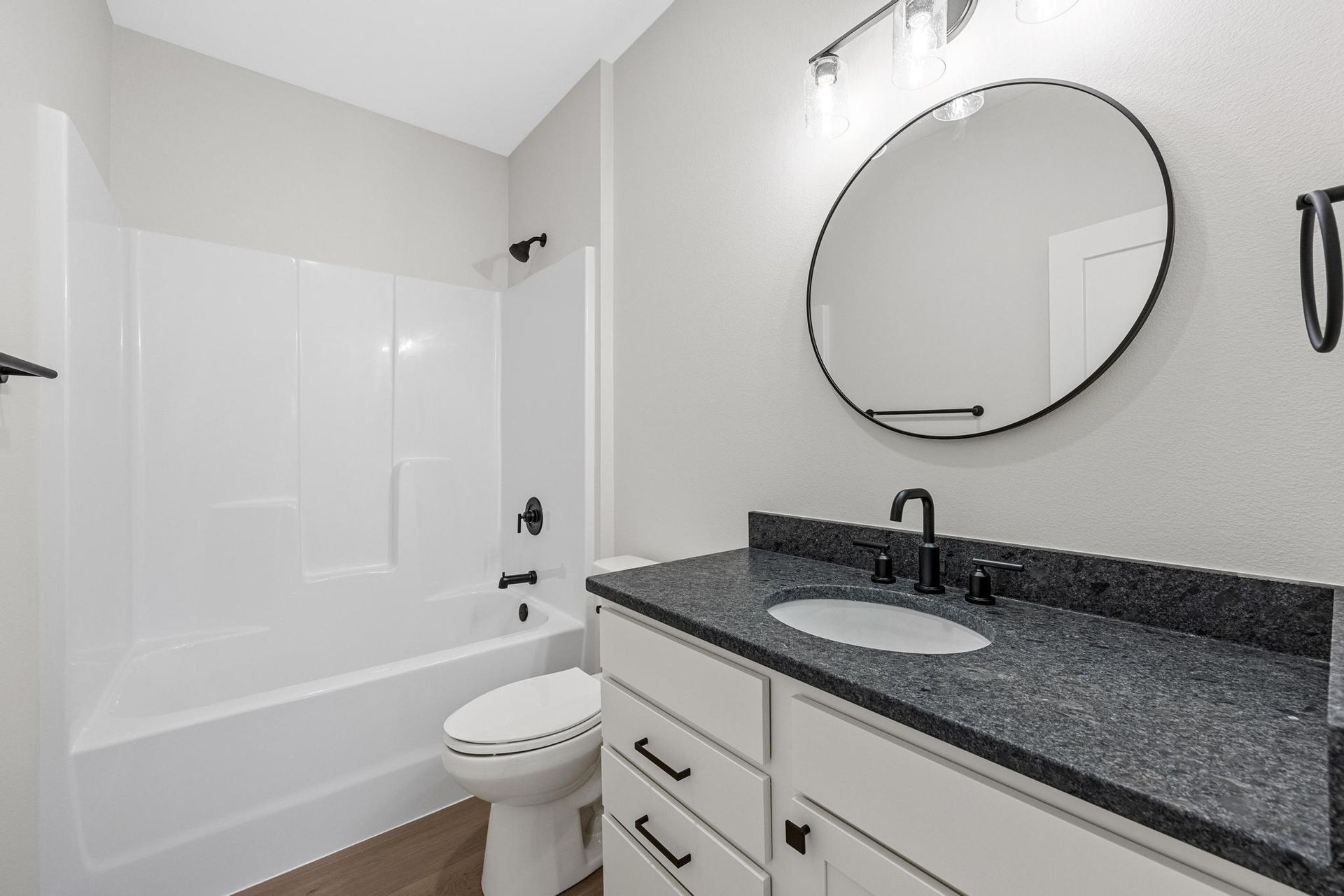 A bathroom with a toilet , sink , bathtub and mirror.