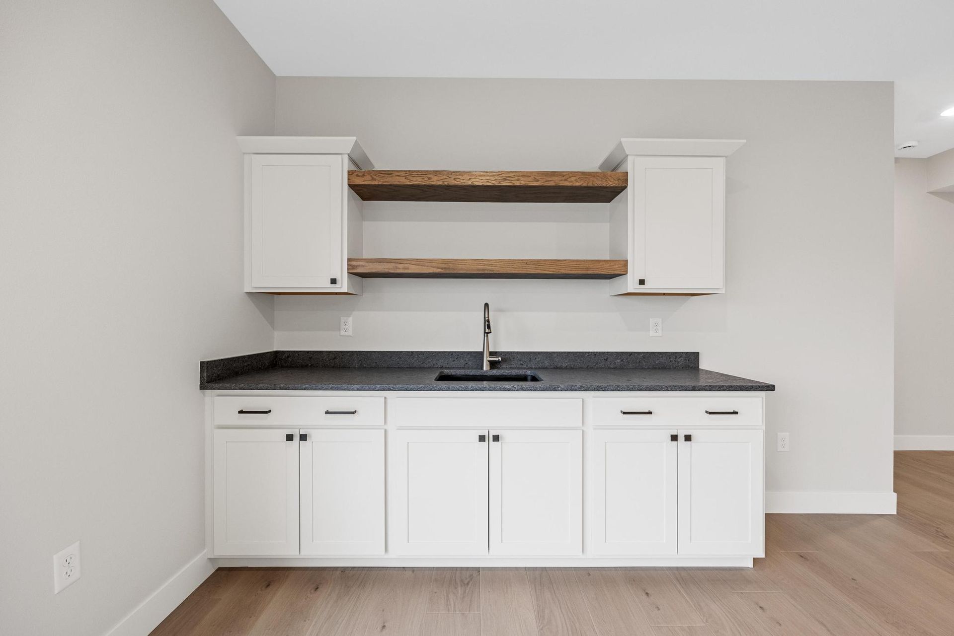 A kitchen with white cabinets , granite counter tops , and a sink.