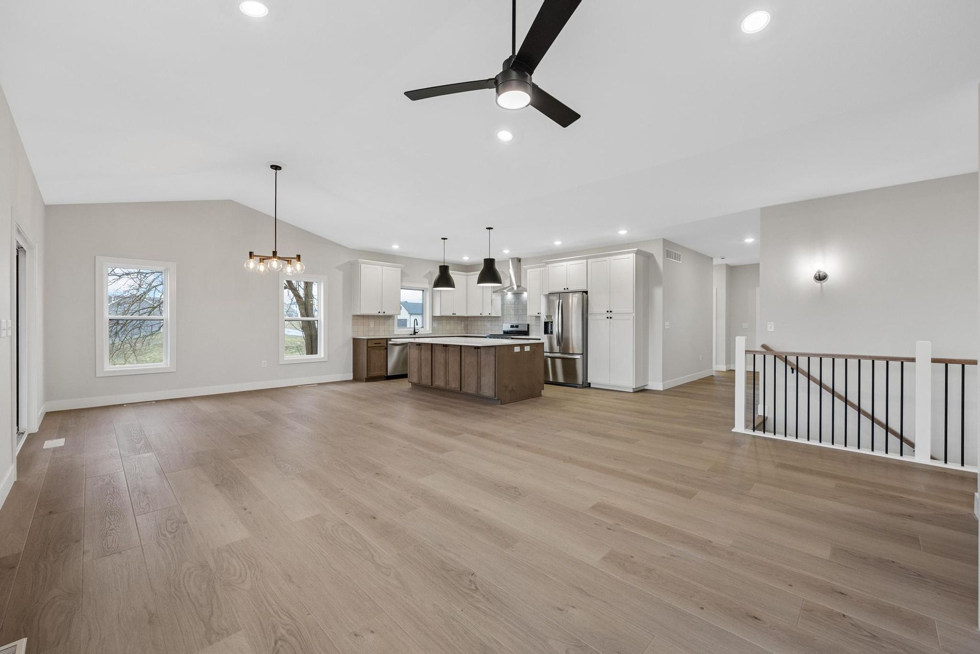 A large empty room with hardwood floors and a ceiling fan.