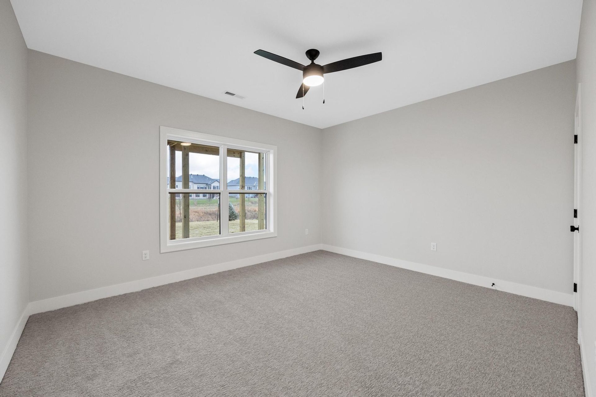 An empty bedroom with a ceiling fan and two windows.