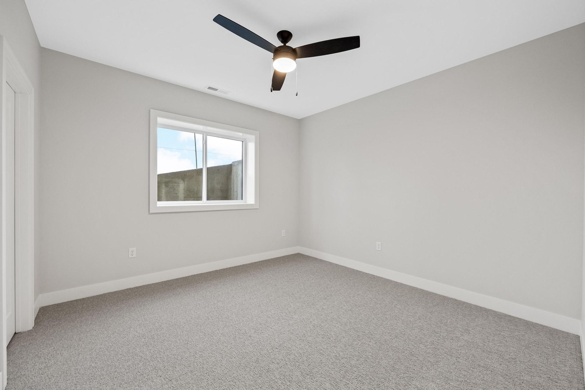 An empty bedroom with a ceiling fan and a window.