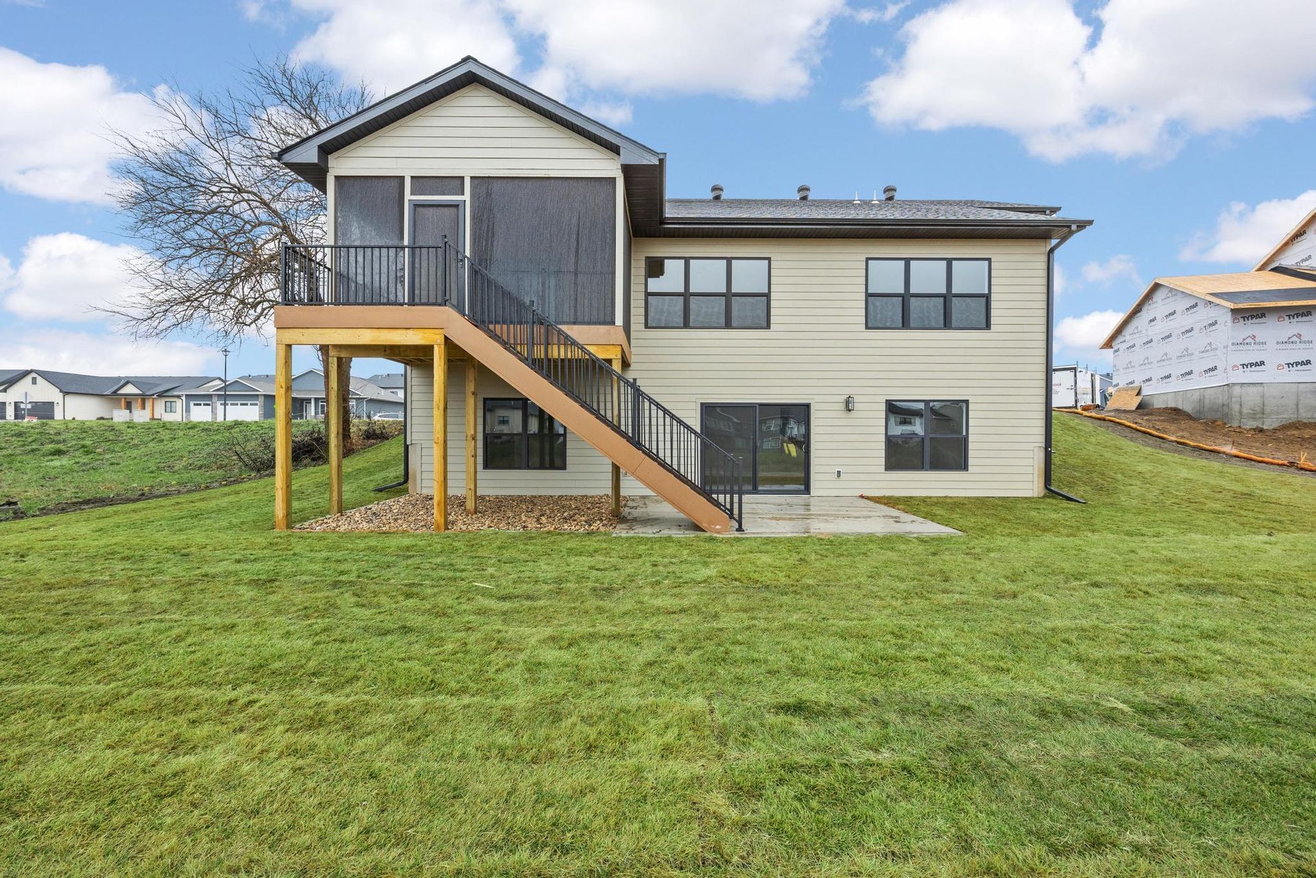 The back of a house with a screened in porch and stairs leading up to it.