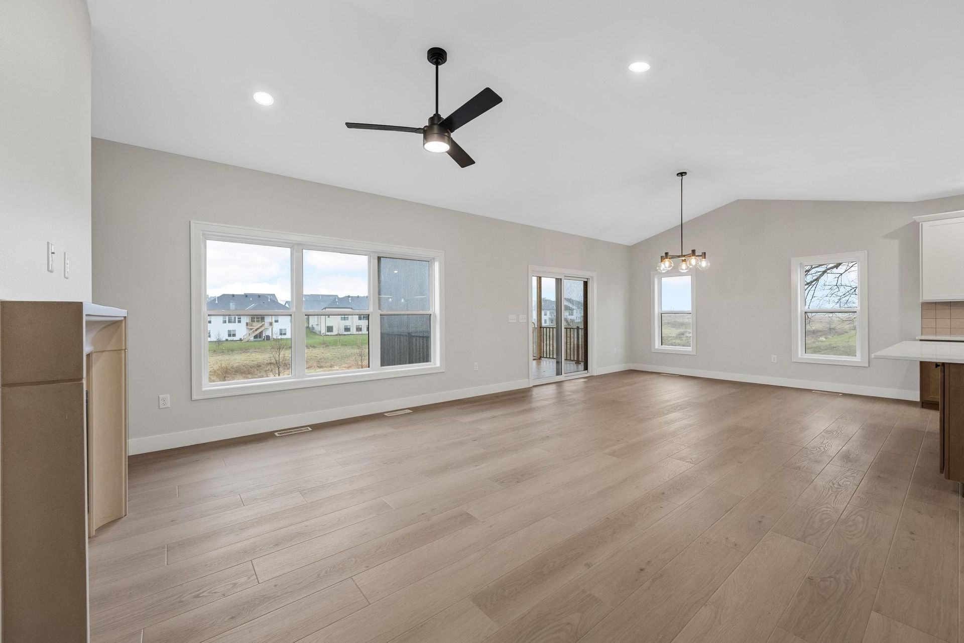 An empty living room with hardwood floors and a ceiling fan.