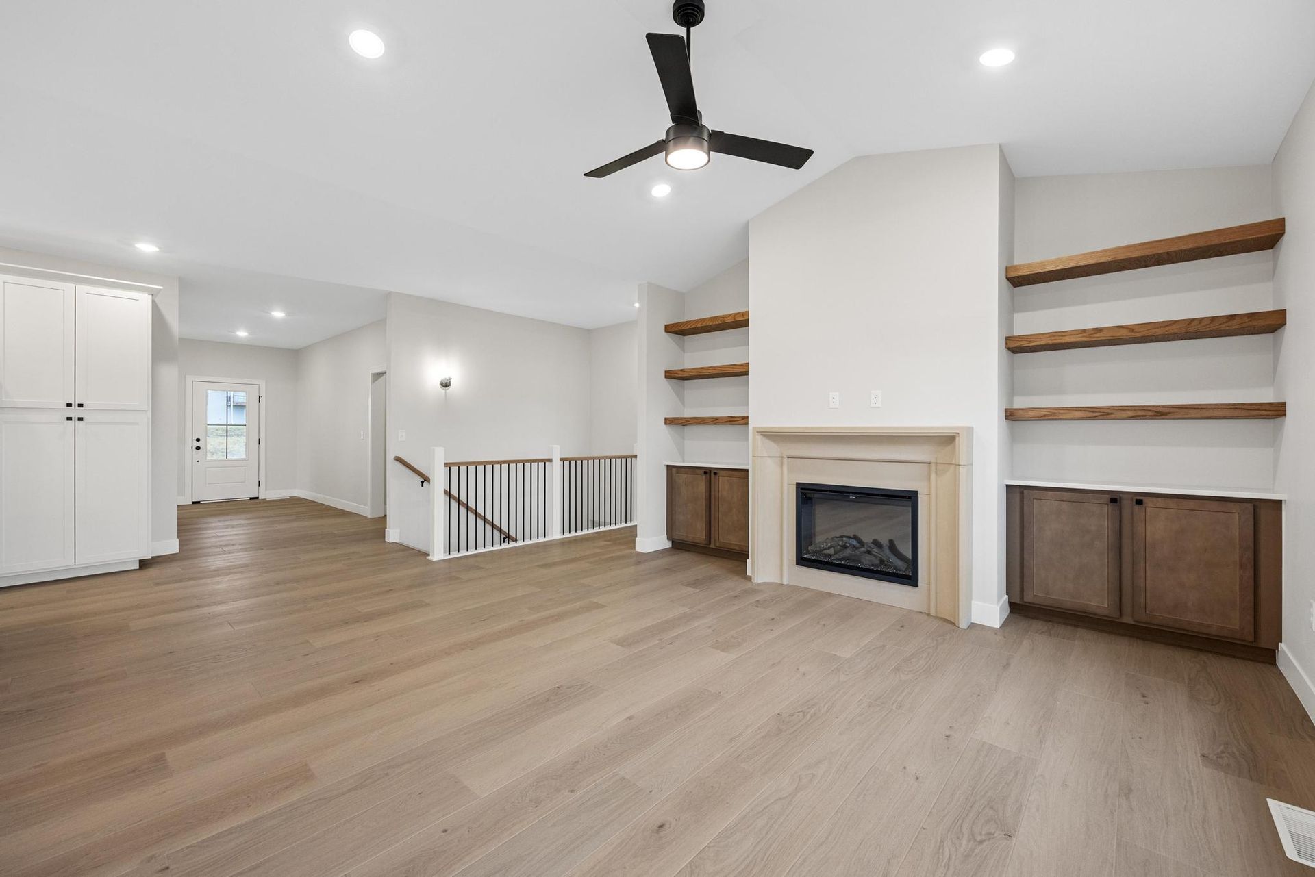 A living room with hardwood floors , a fireplace and a ceiling fan.
