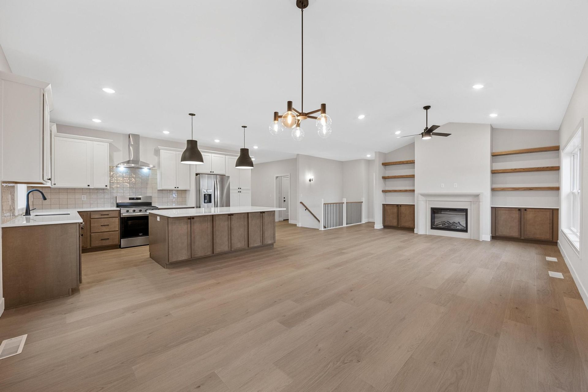 A kitchen and living room in a house with hardwood floors and a fireplace.
