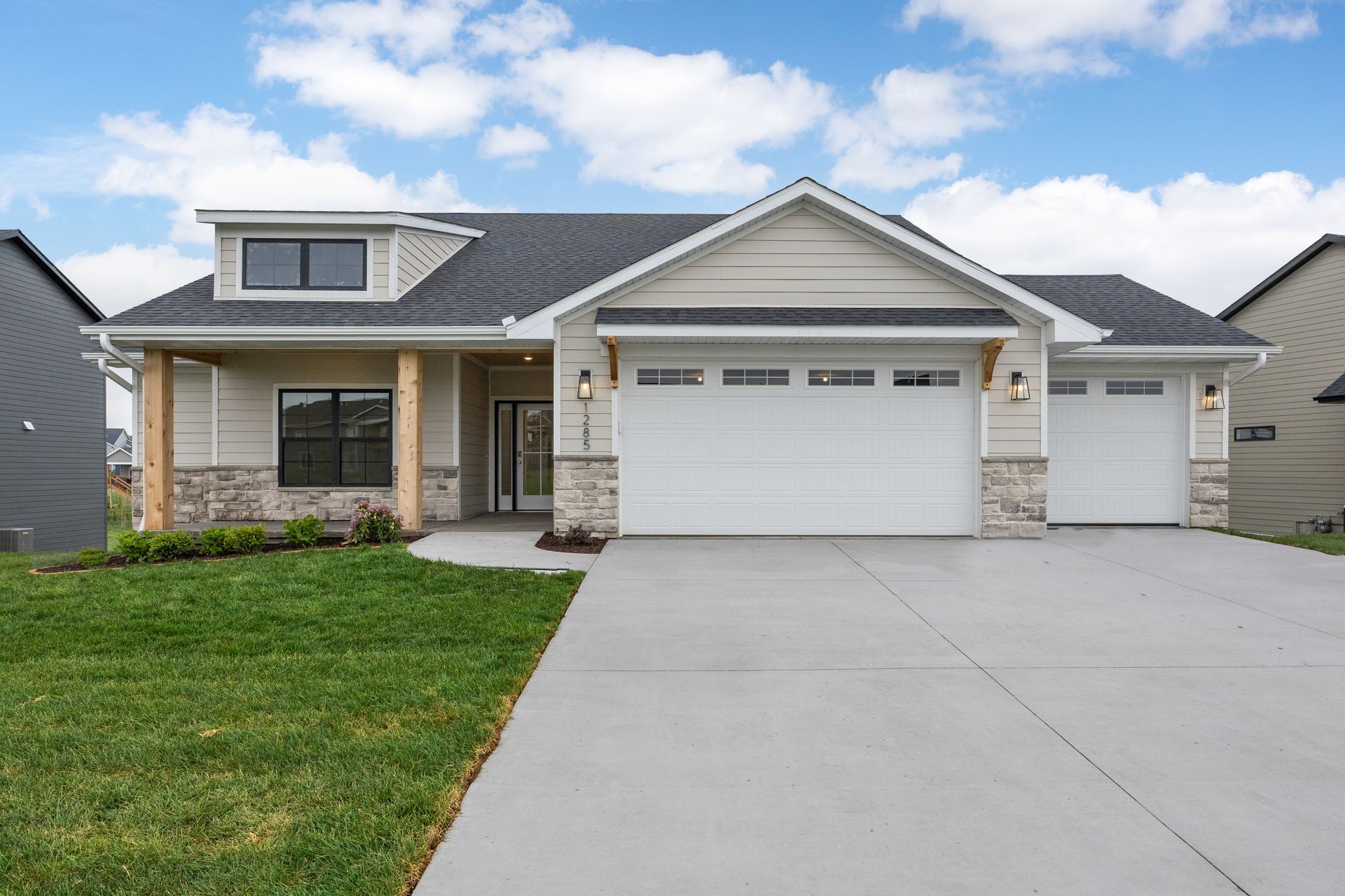 The front of a house with a white garage door and a concrete driveway.