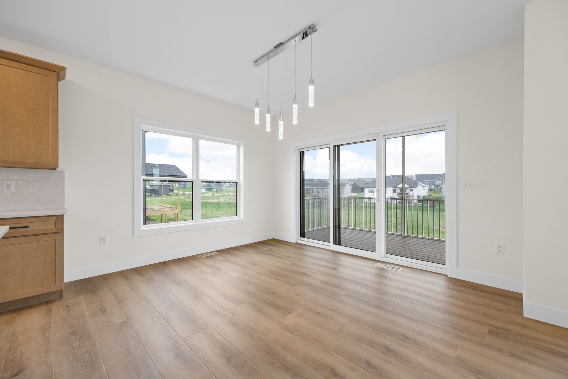 An empty living room with hardwood floors and sliding glass doors.