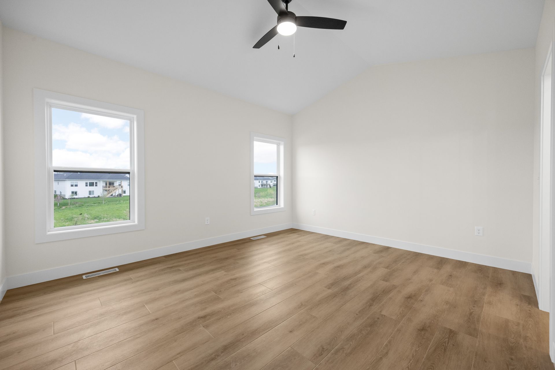 An empty room with hardwood floors and a ceiling fan.