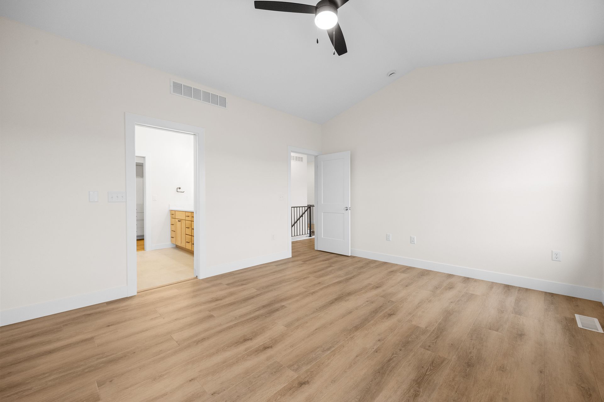 A large empty room with hardwood floors and a ceiling fan.
