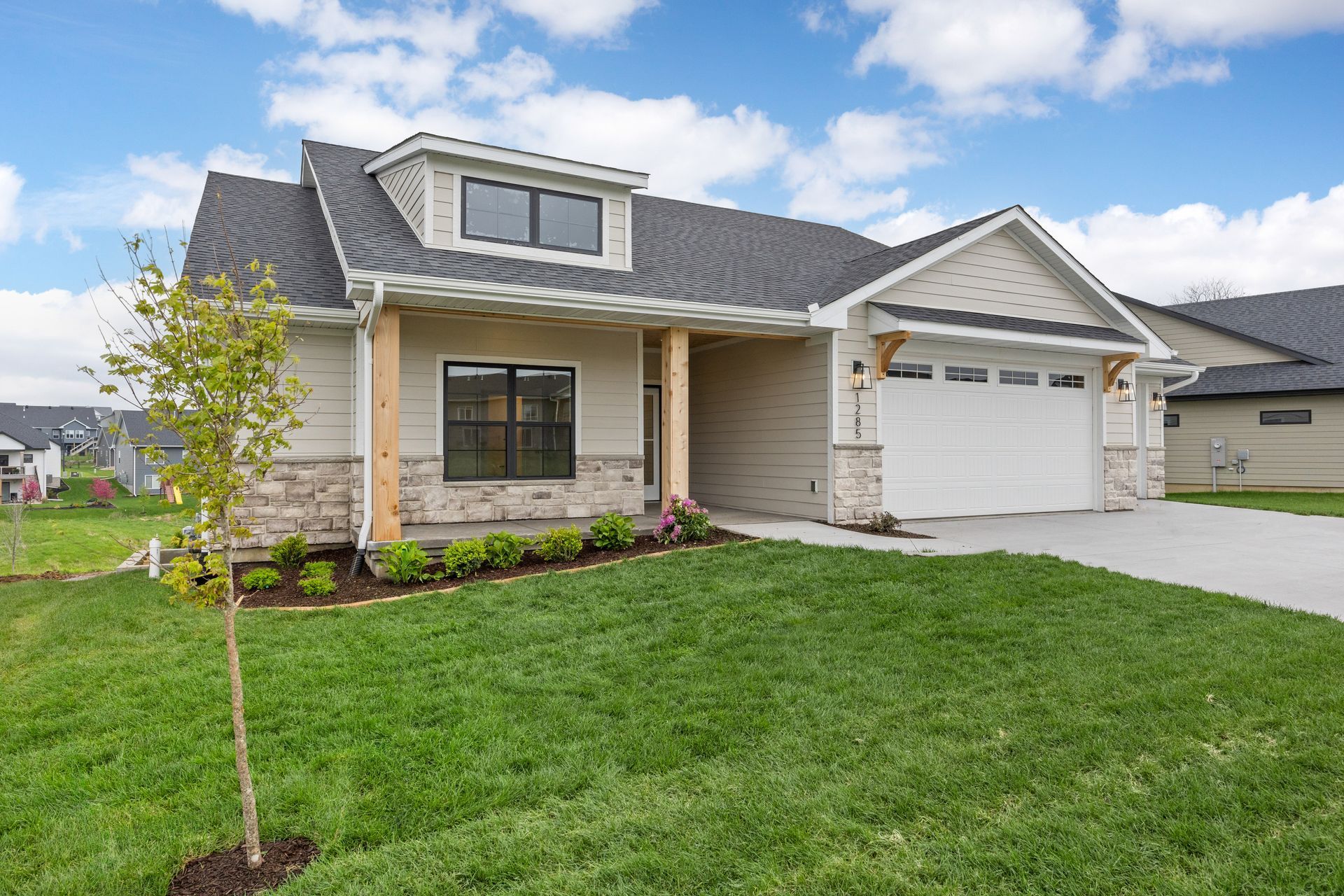 A house with a garage and a large lawn in front of it.