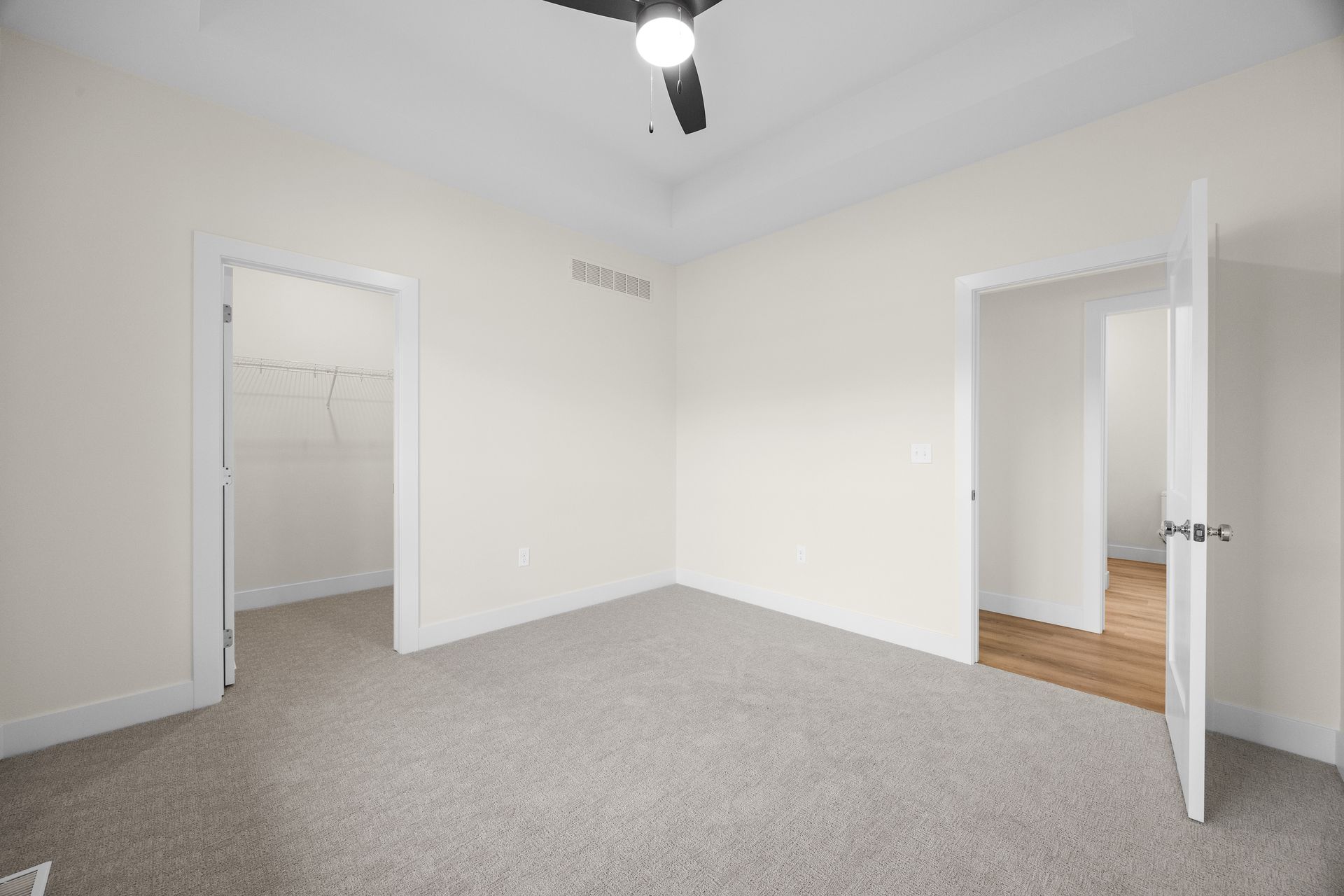 An empty bedroom with a ceiling fan and a walk in closet.
