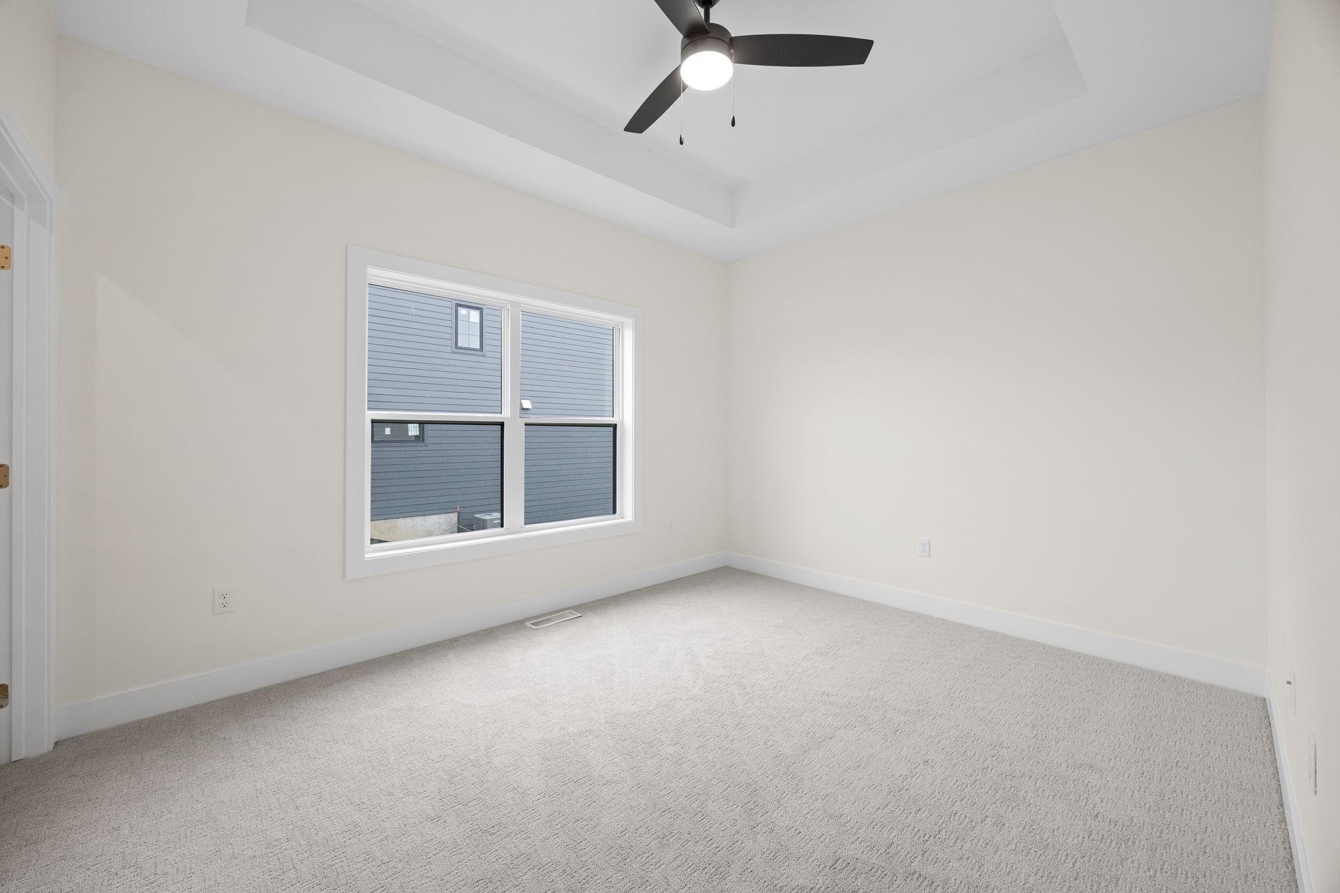 An empty bedroom with a ceiling fan and a window.
