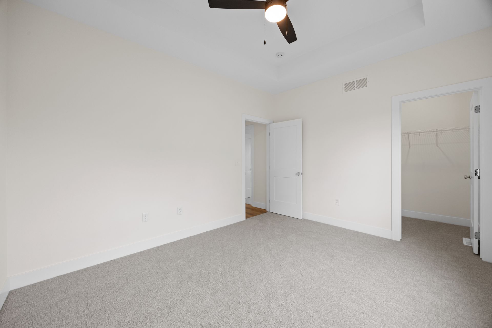 An empty bedroom with a ceiling fan and a walk in closet.