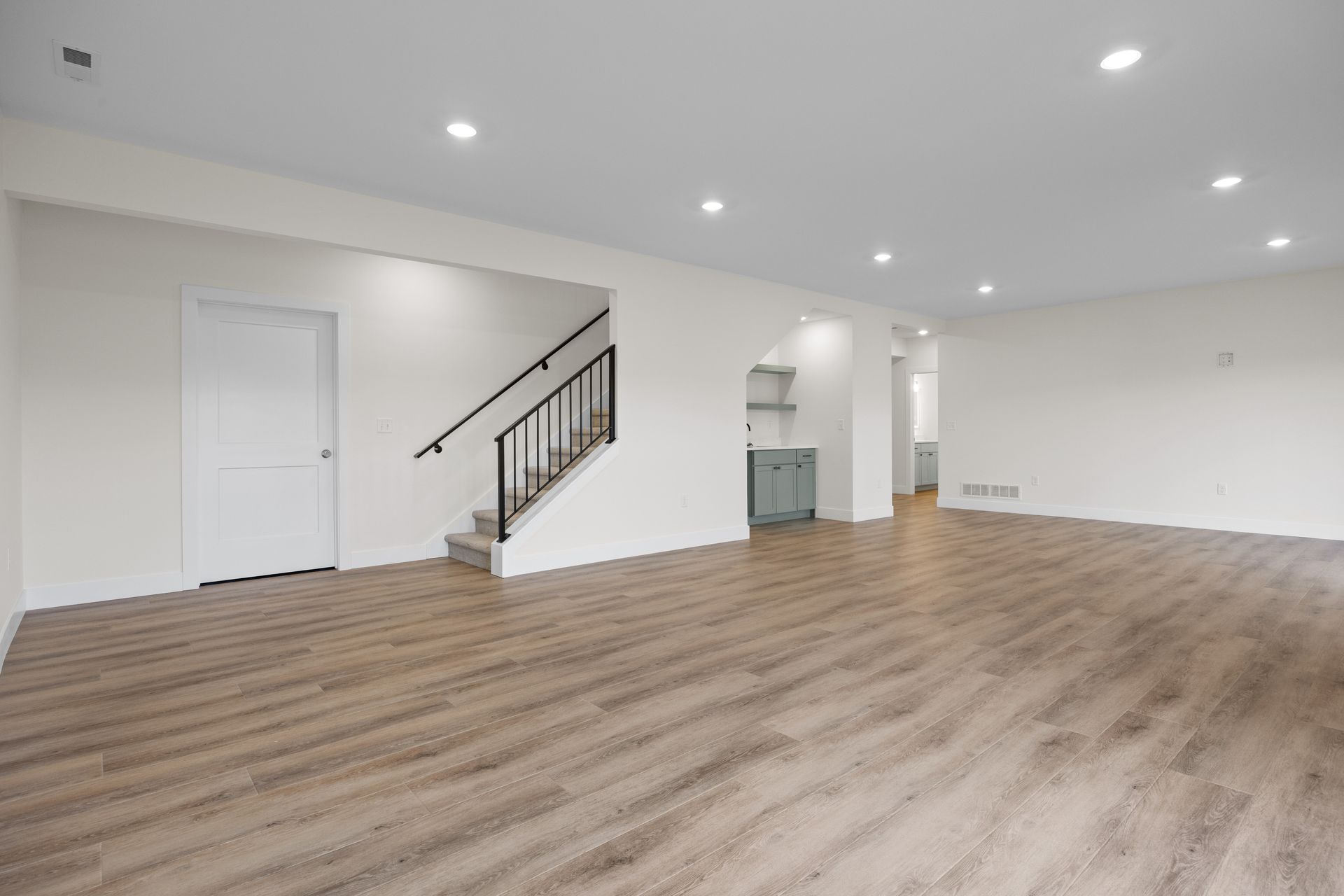 A large empty room with hardwood floors and white walls.