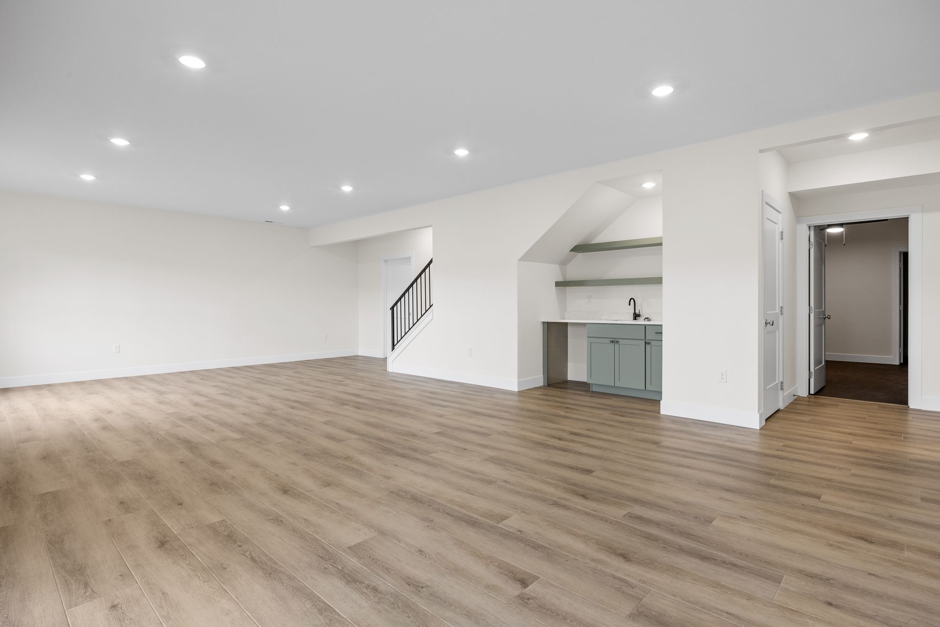 A large empty room with hardwood floors and white walls.