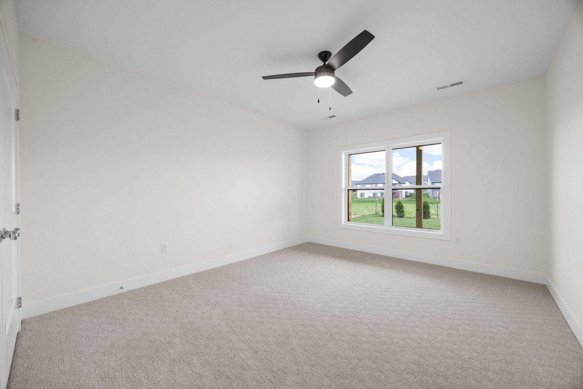 An empty bedroom with a ceiling fan and two windows.