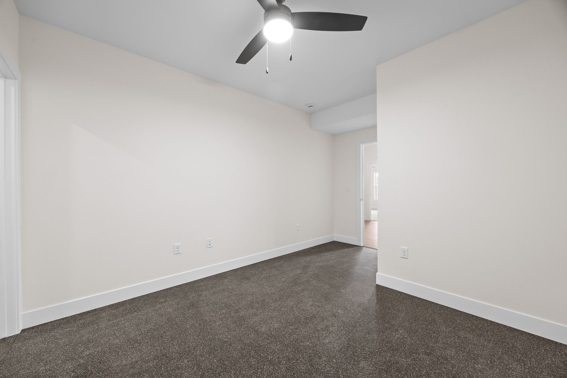 An empty bedroom with a ceiling fan and a door.