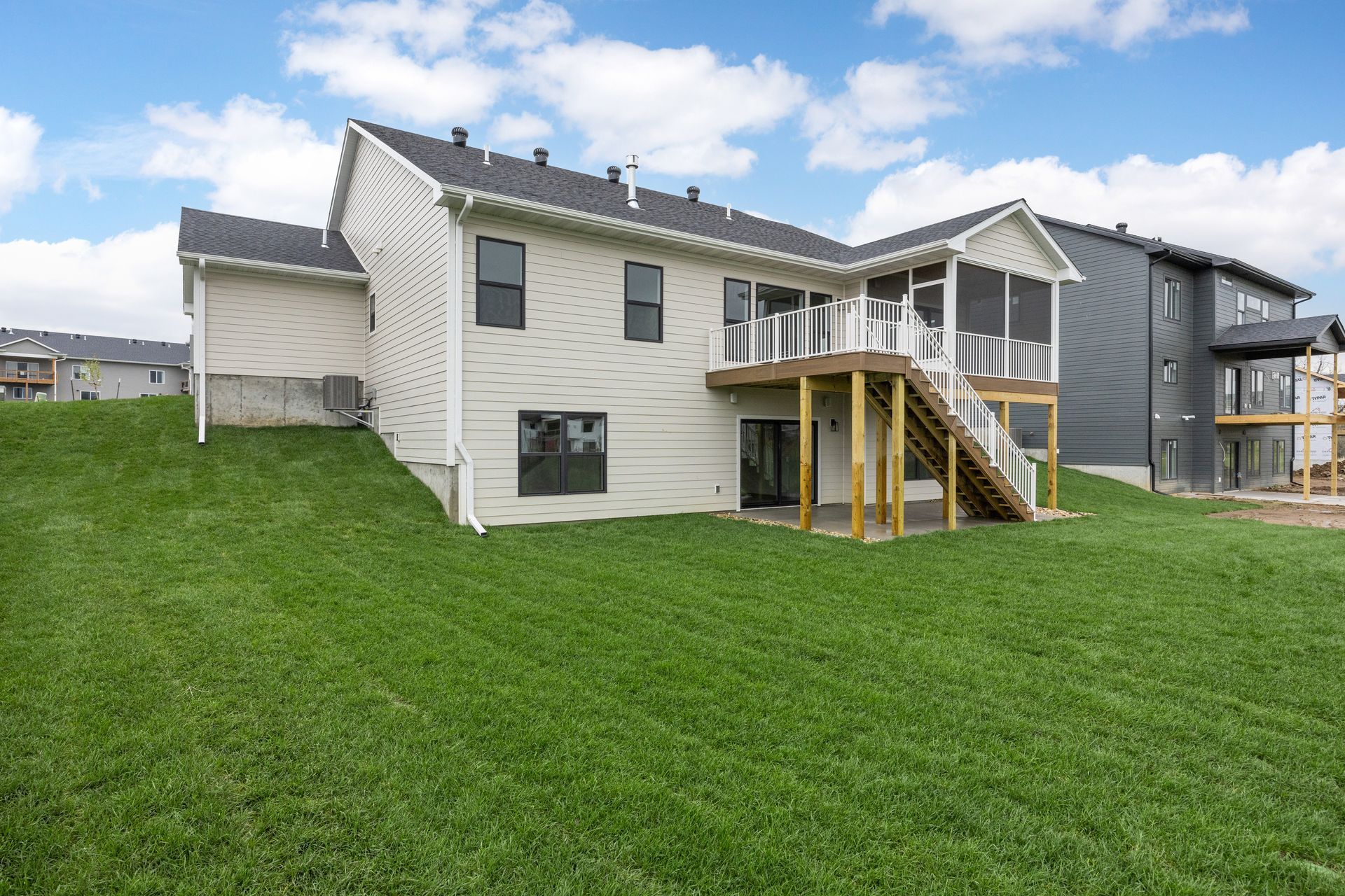 The back of a house with a screened in porch and a large lawn.