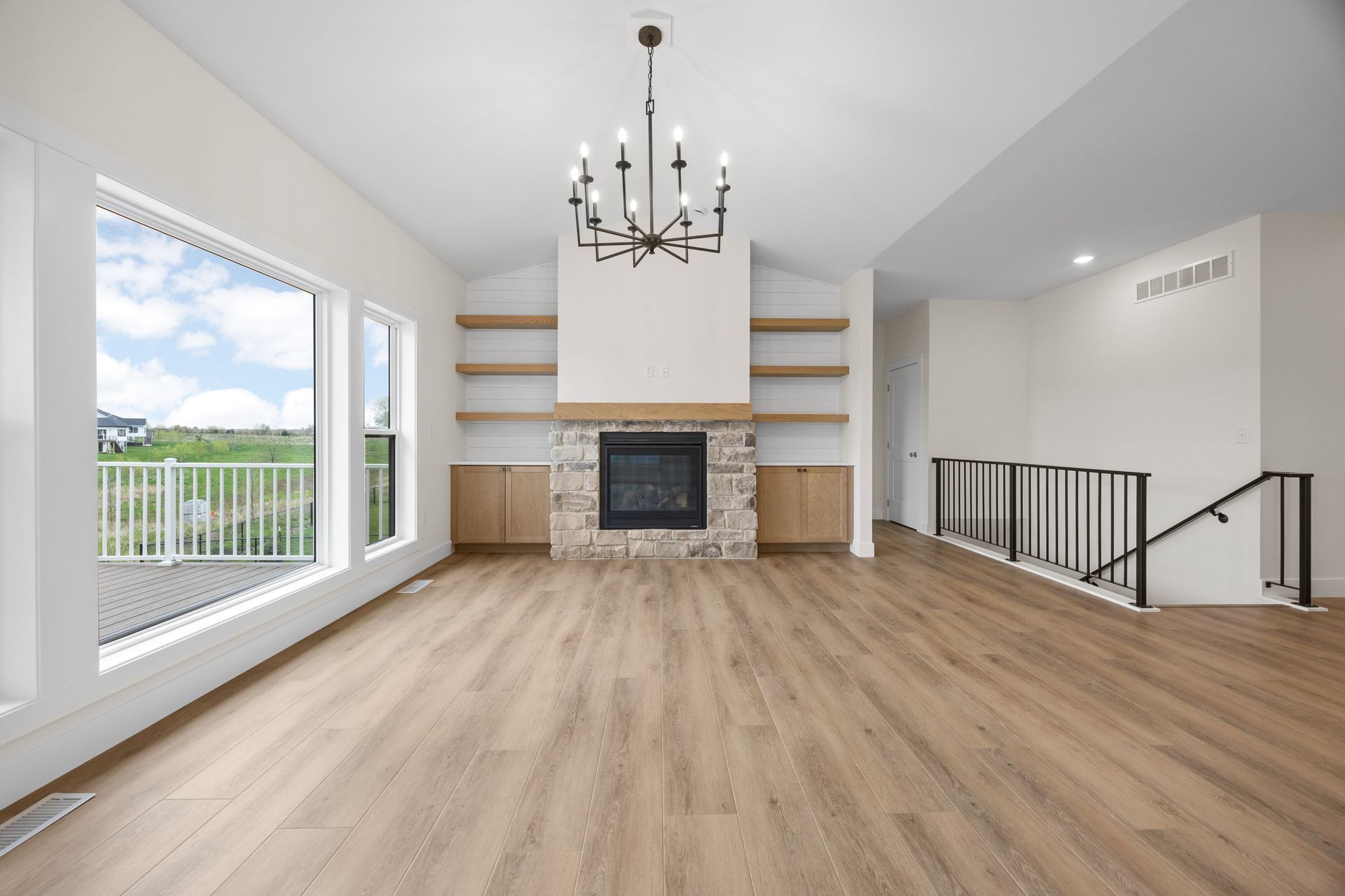 An empty living room with hardwood floors , a fireplace and a chandelier.