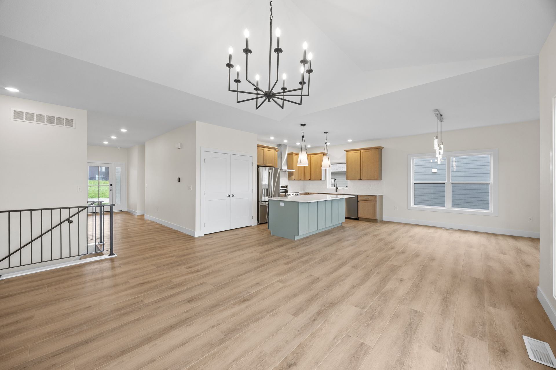 A large empty room with hardwood floors and a chandelier.