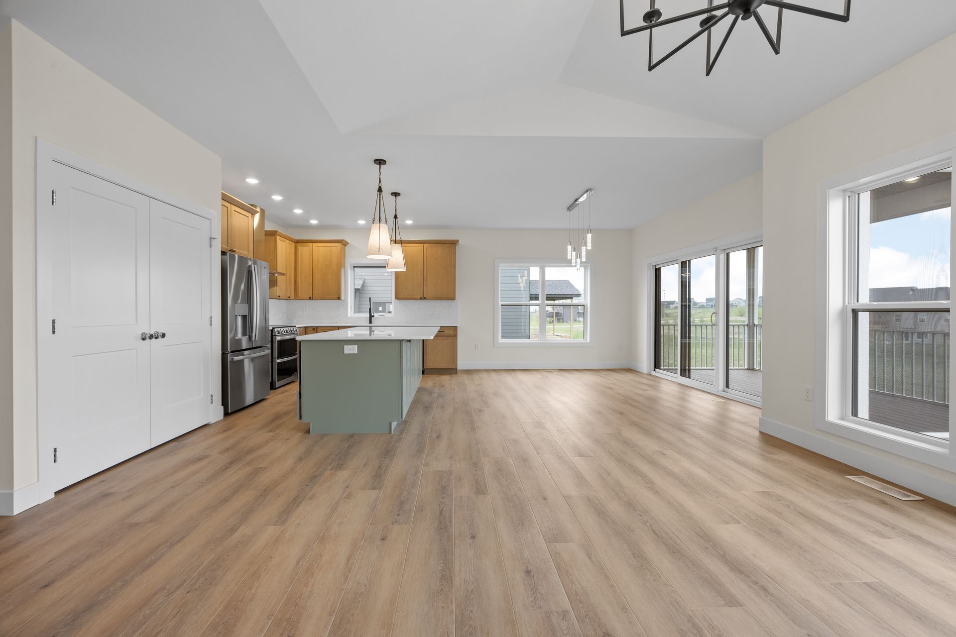 A large empty room with hardwood floors and a kitchen.