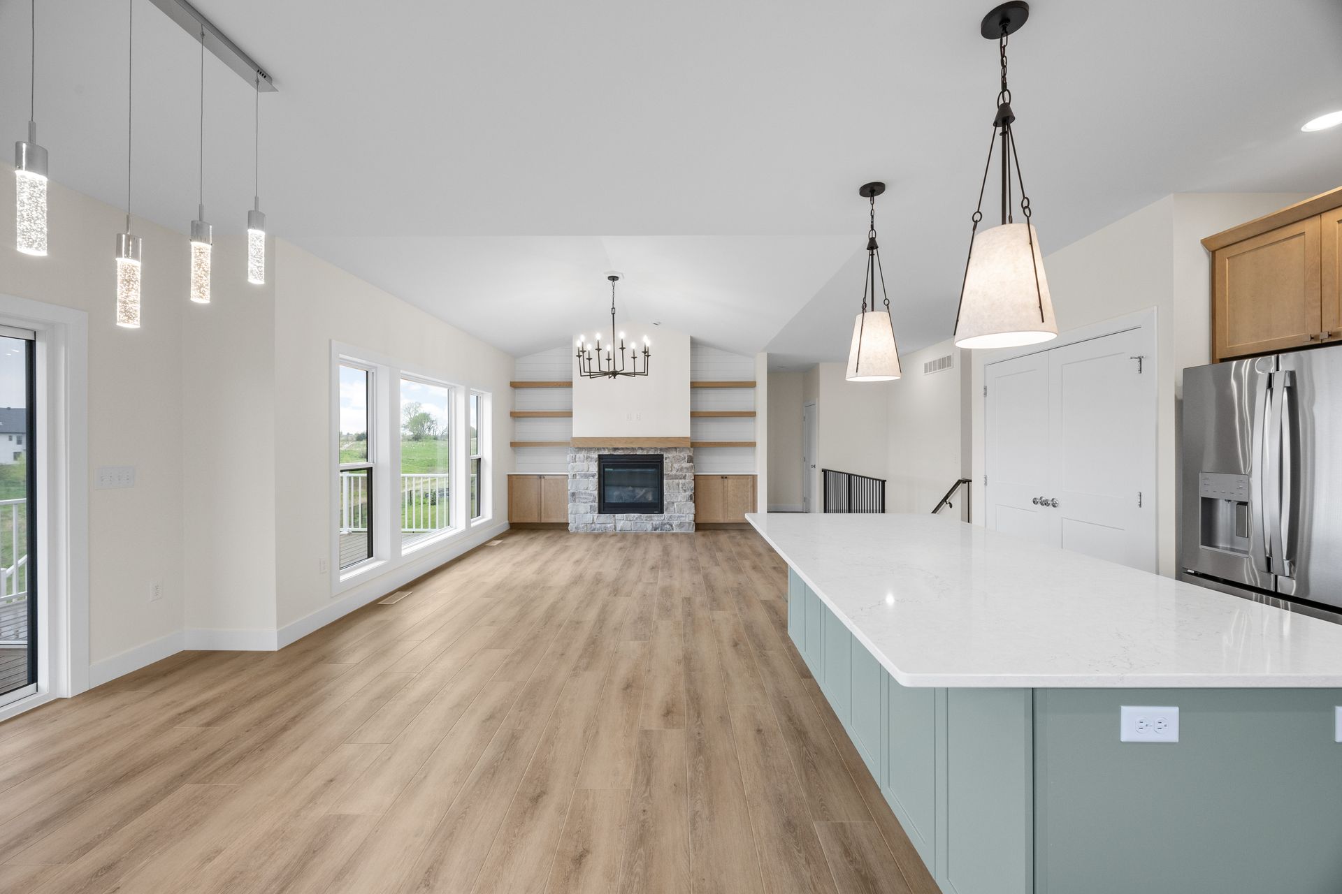 An empty kitchen with a large island and a fireplace.