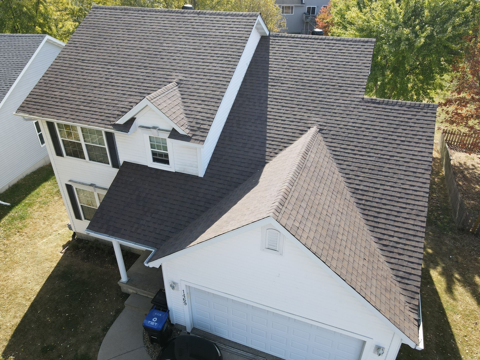 An aerial view of a white house with a brown roof
