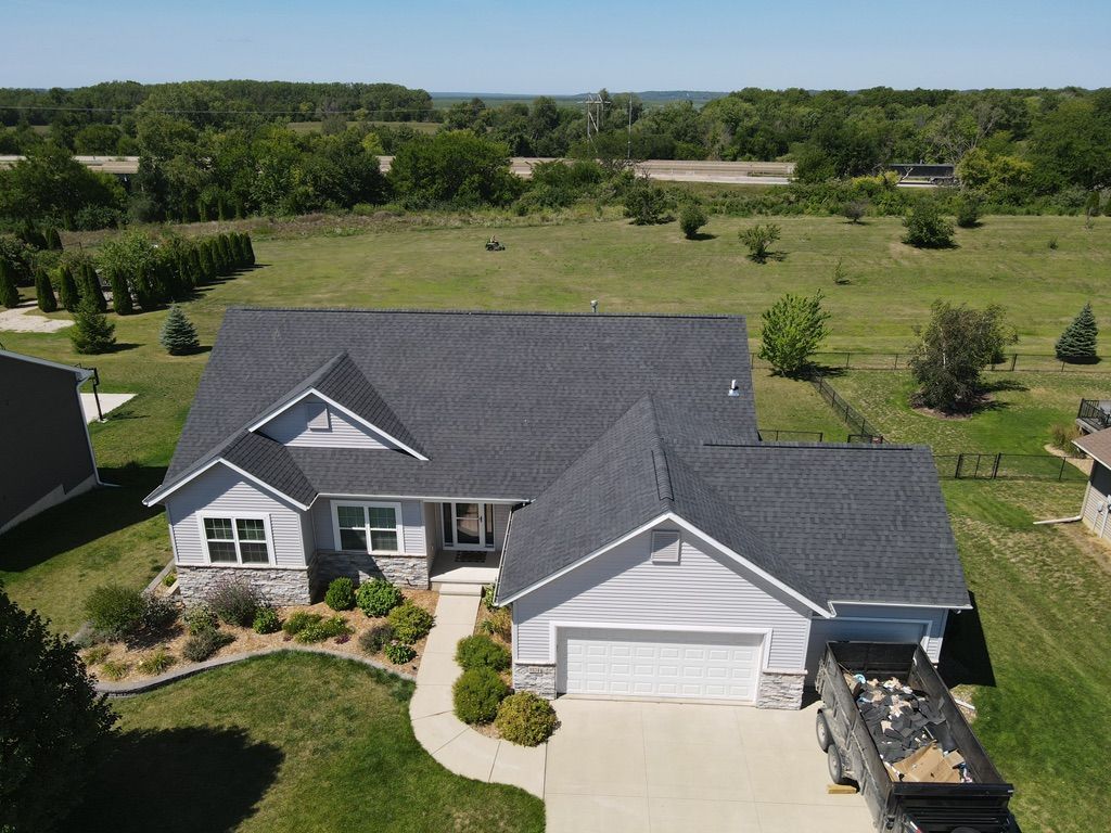 An aerial view of a house with a new roof and a truck parked in front of it.
