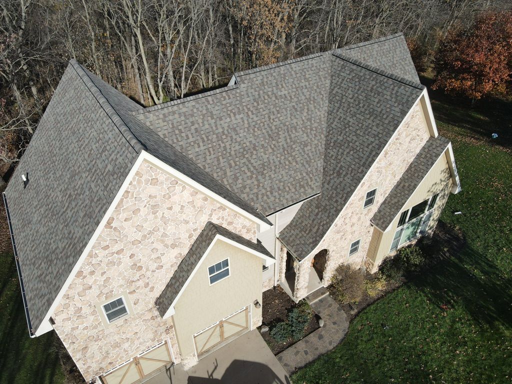 An aerial view of a large brick house with a gray roof.