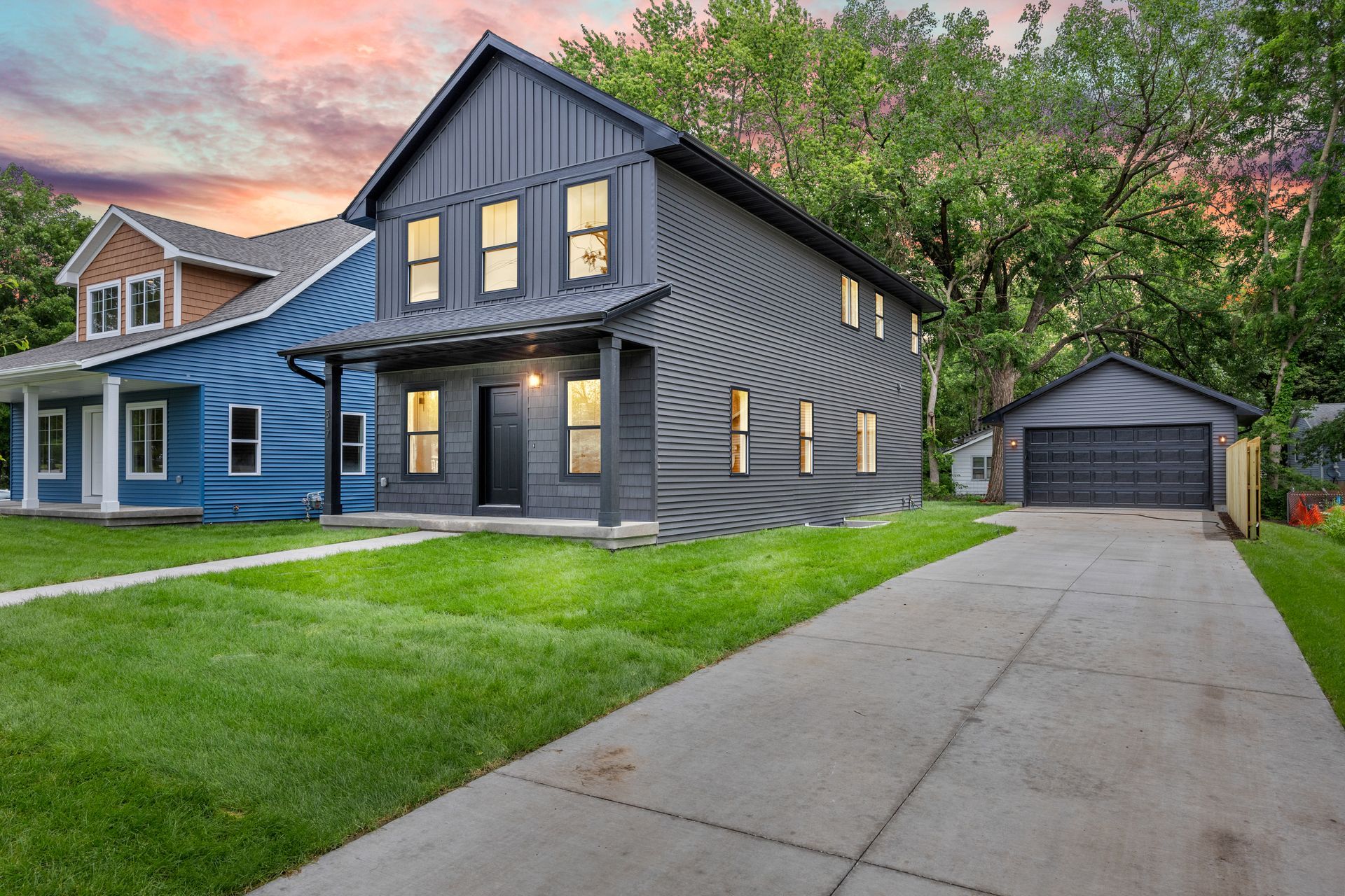 A couple of houses are sitting next to each other on a lush green lawn.