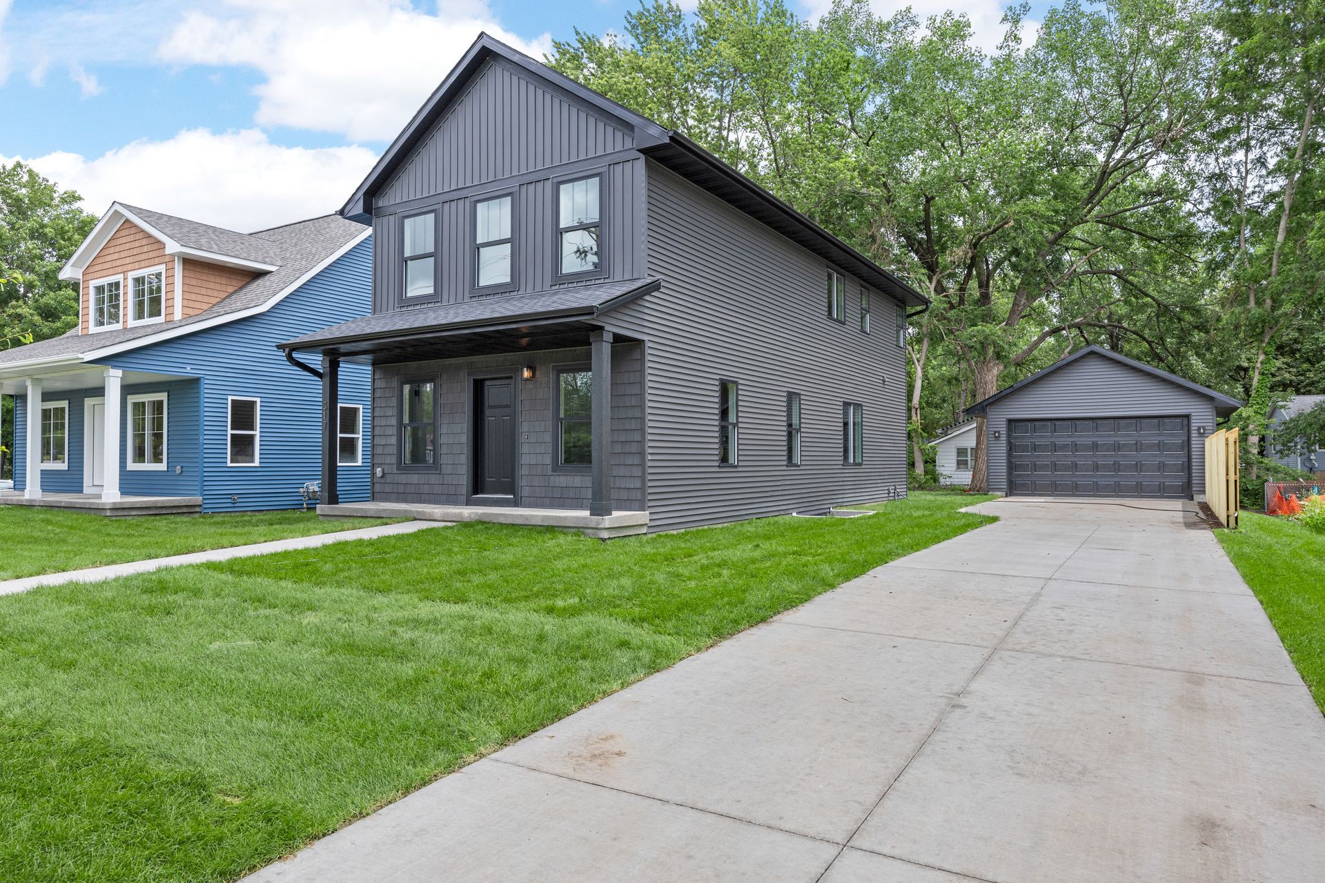 A couple of houses are sitting next to each other on a lush green lawn.