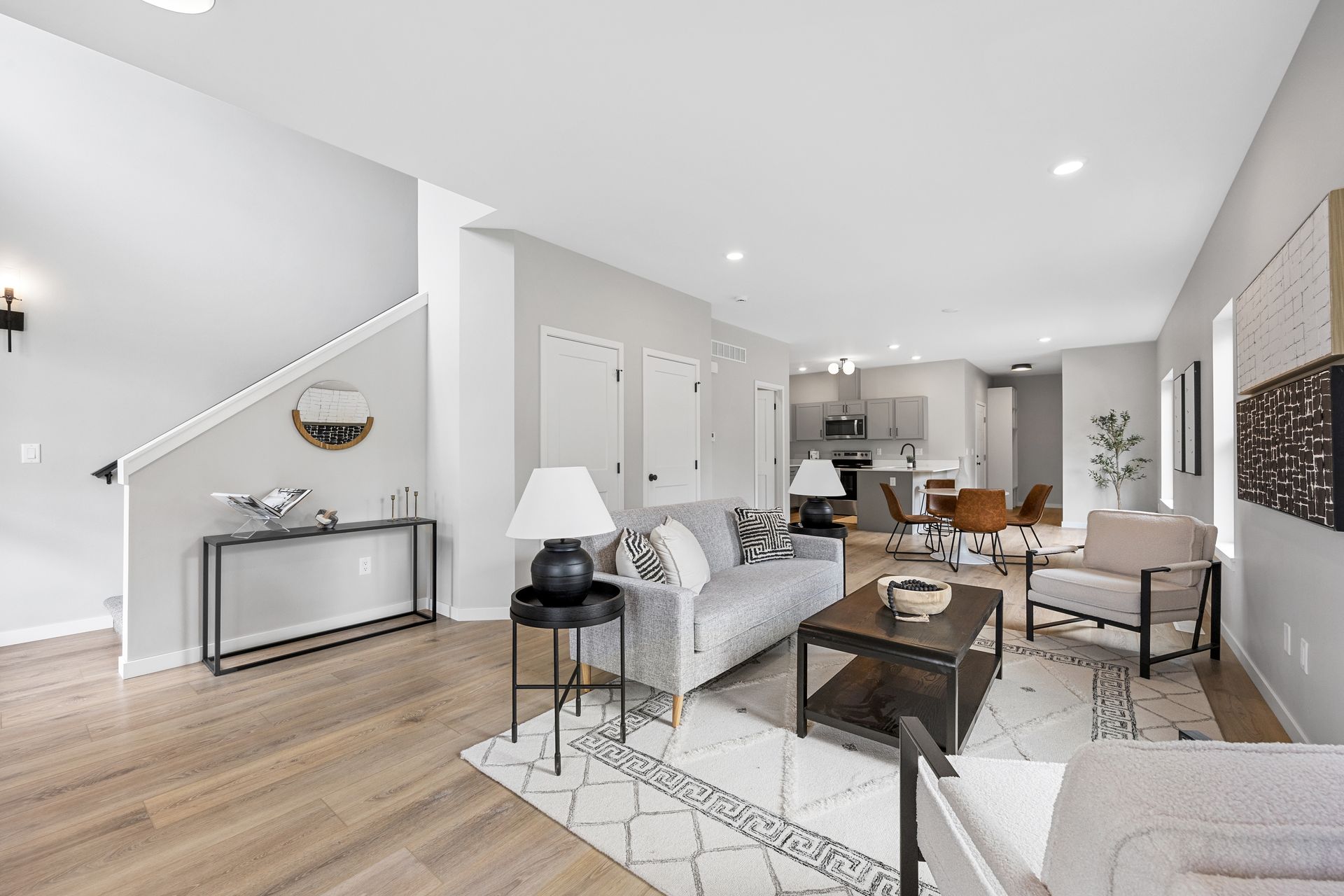 A living room with a couch , chairs , coffee table and stairs.