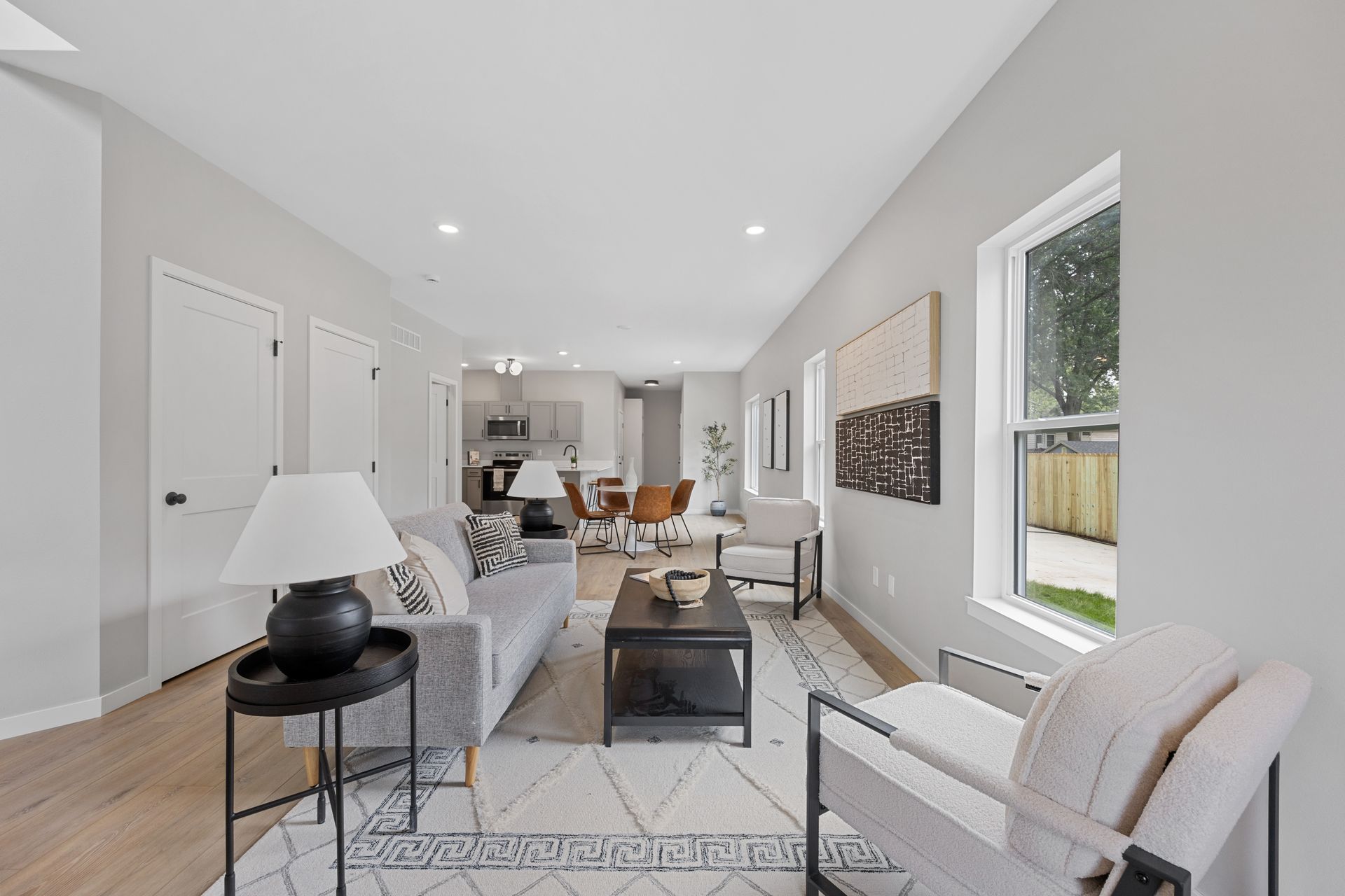 A living room with a couch , chair , coffee table and lamp.