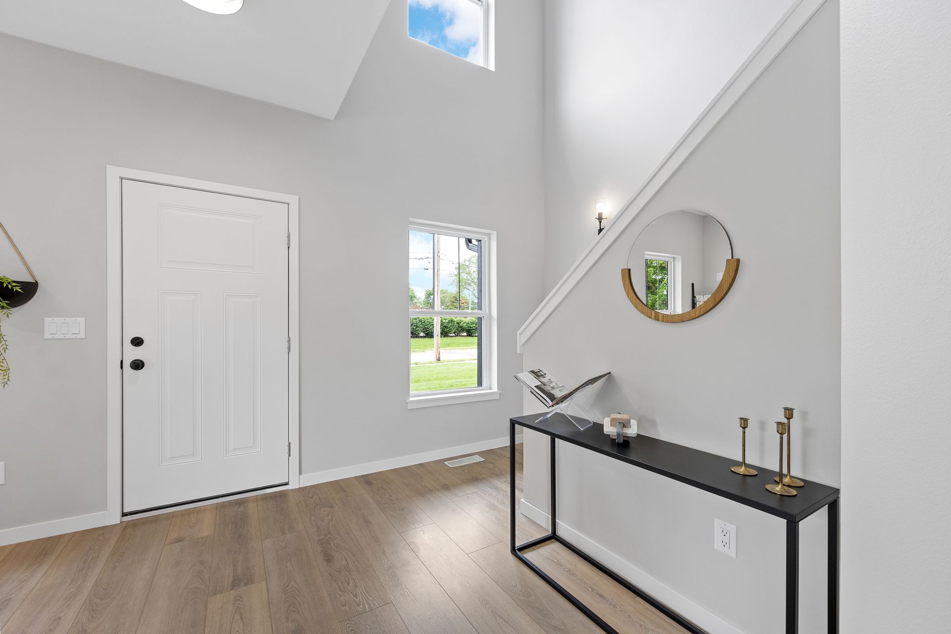 A hallway with a table , mirror and stairs in a house.