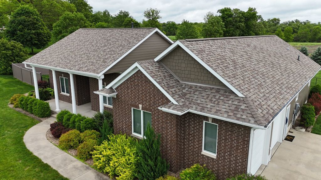 An aerial view of a large brick house with a gray roof.