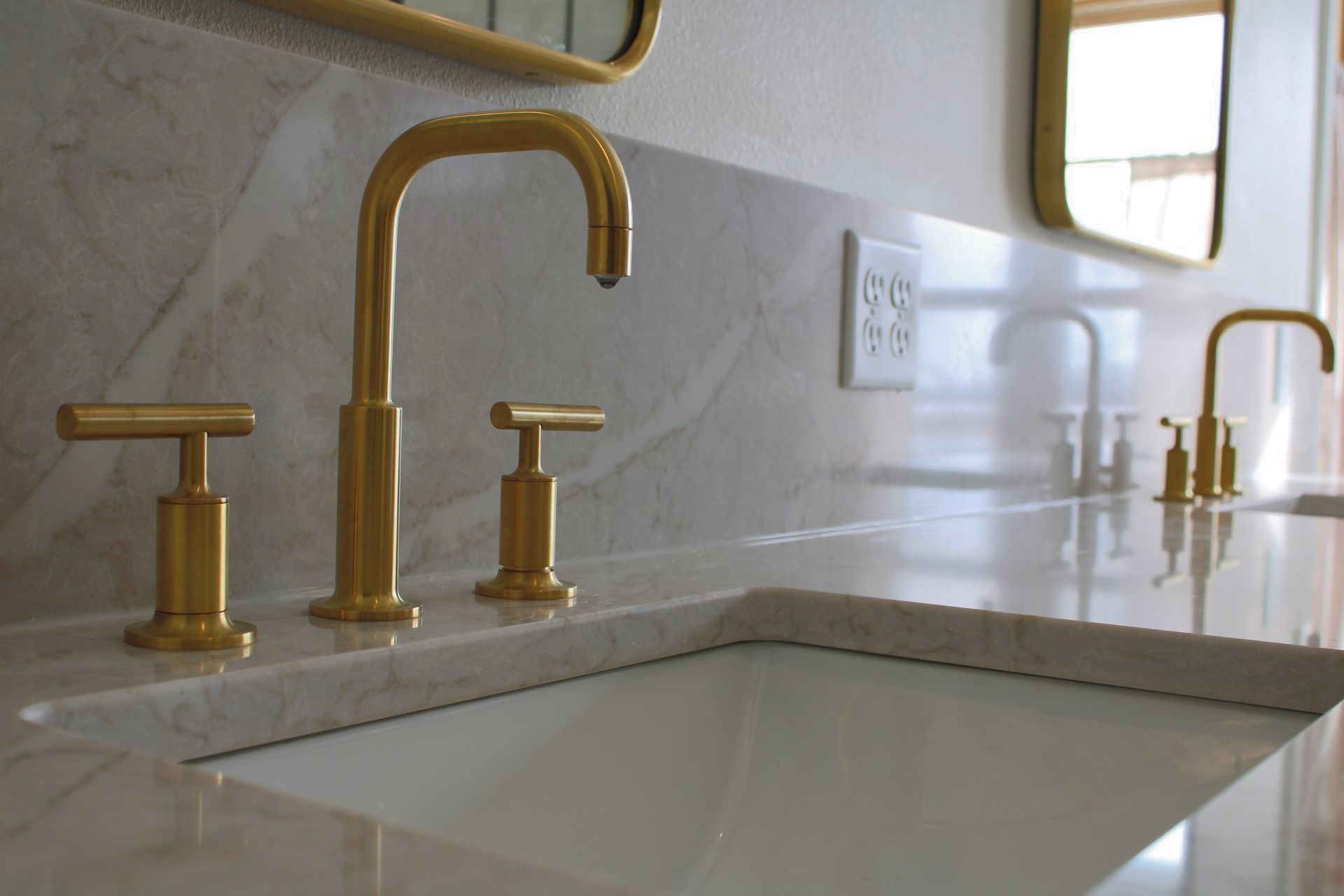 A bathroom sink with gold faucets and a mirror