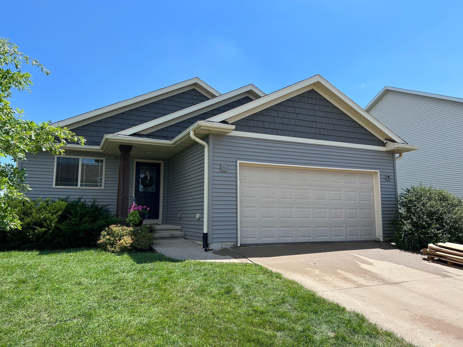 A gray house with a white garage door and a blue sky in the background