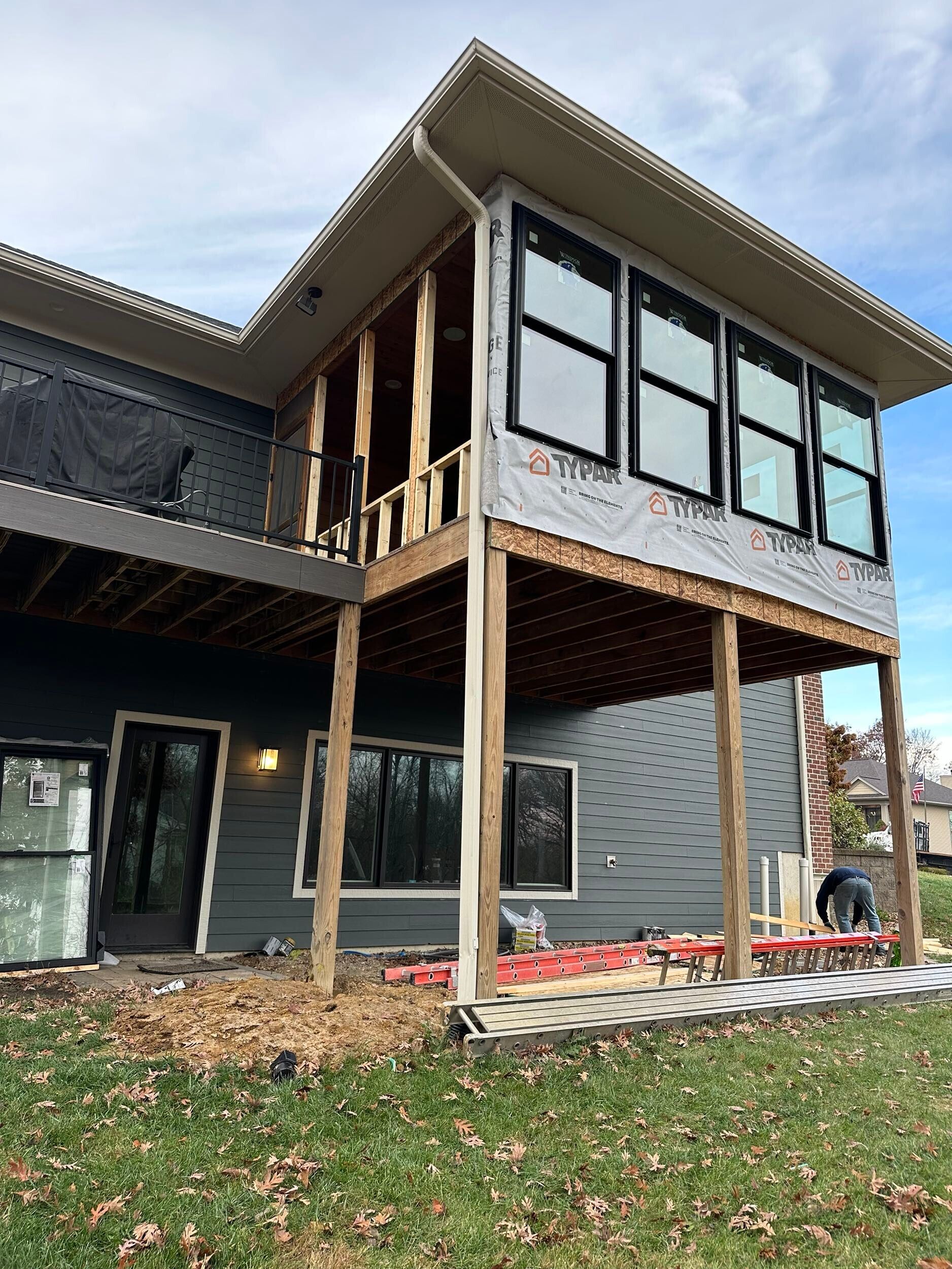 A house is being built with a deck and a lot of windows.