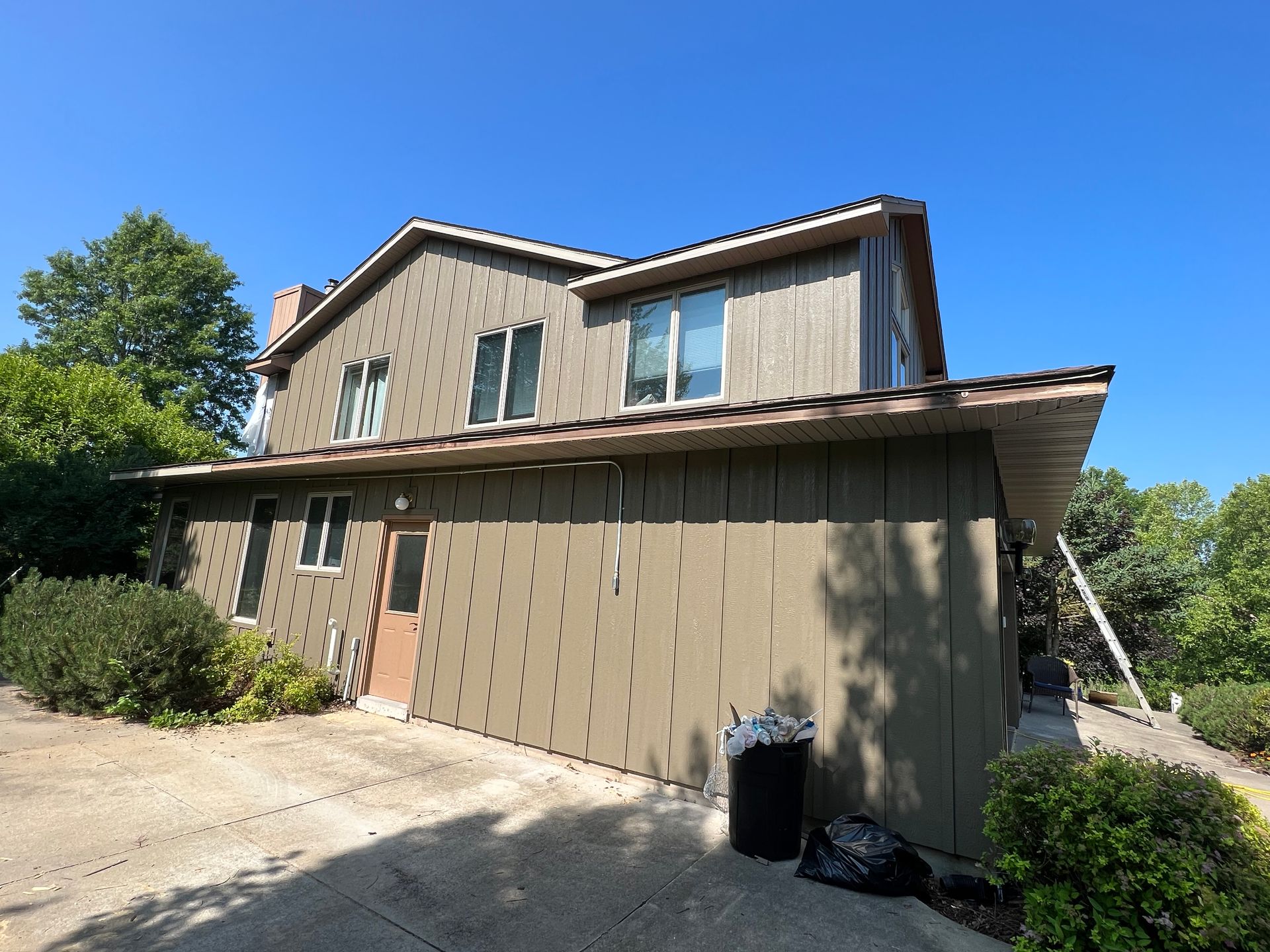 A large house with a lot of windows and a trash can in front of it