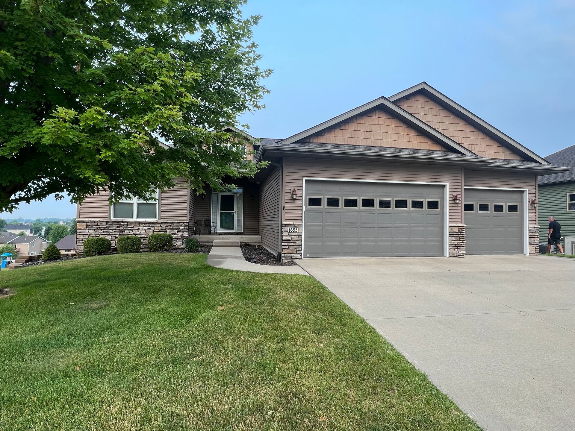 A house with two garage doors and a tree in front of it