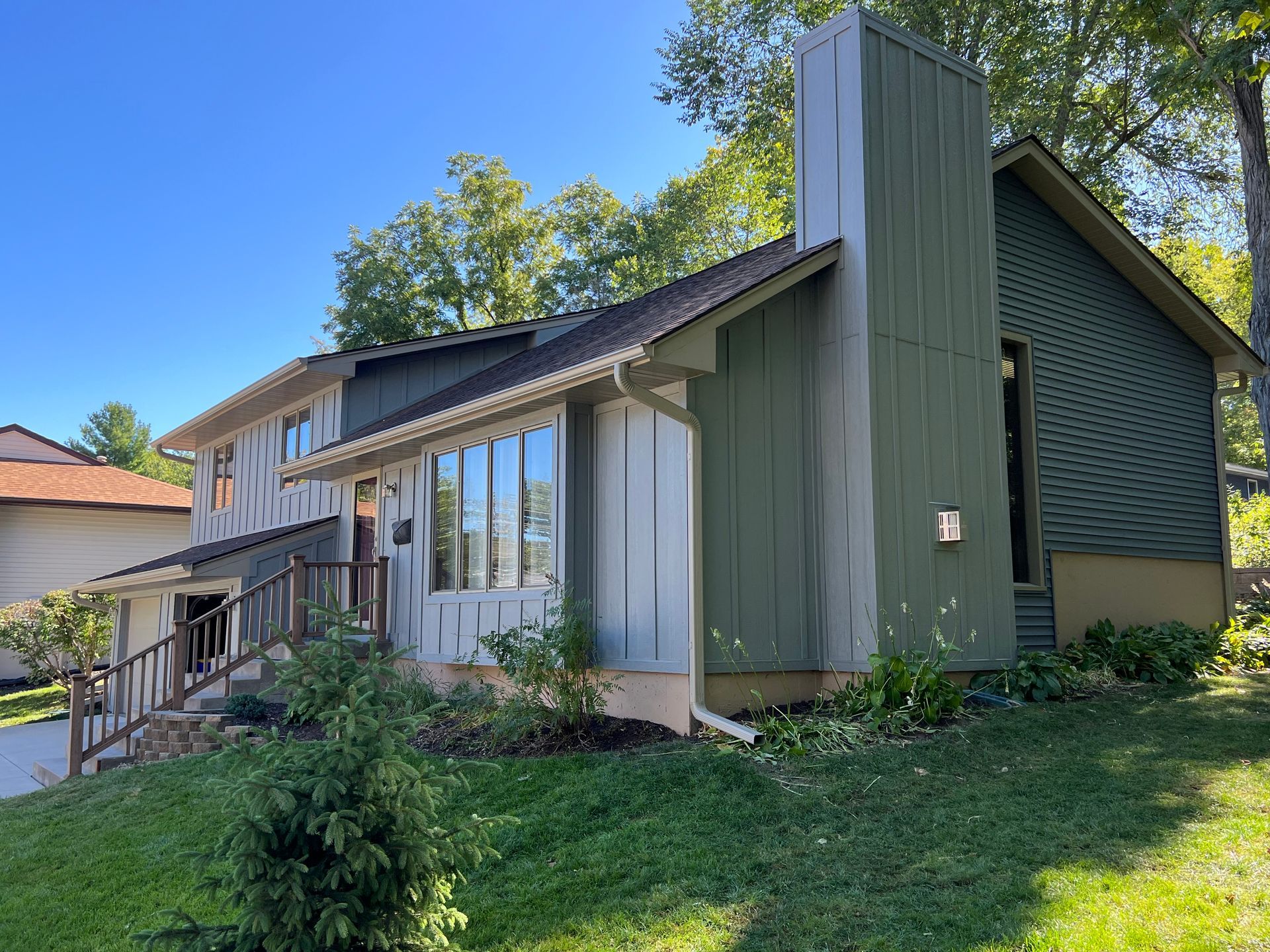 A large house with a lot of windows is sitting on top of a lush green lawn.