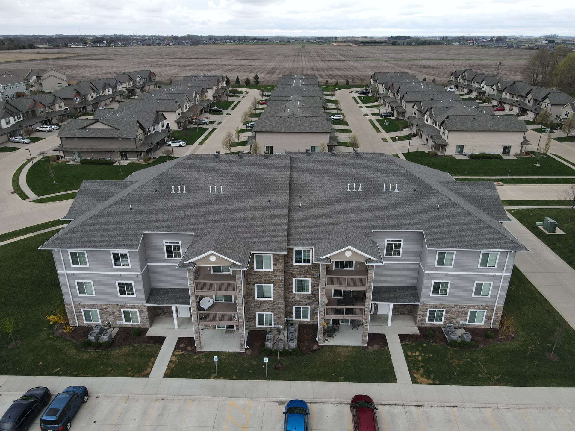 An aerial view of a apartment complex with a lot of cars parked in front of it