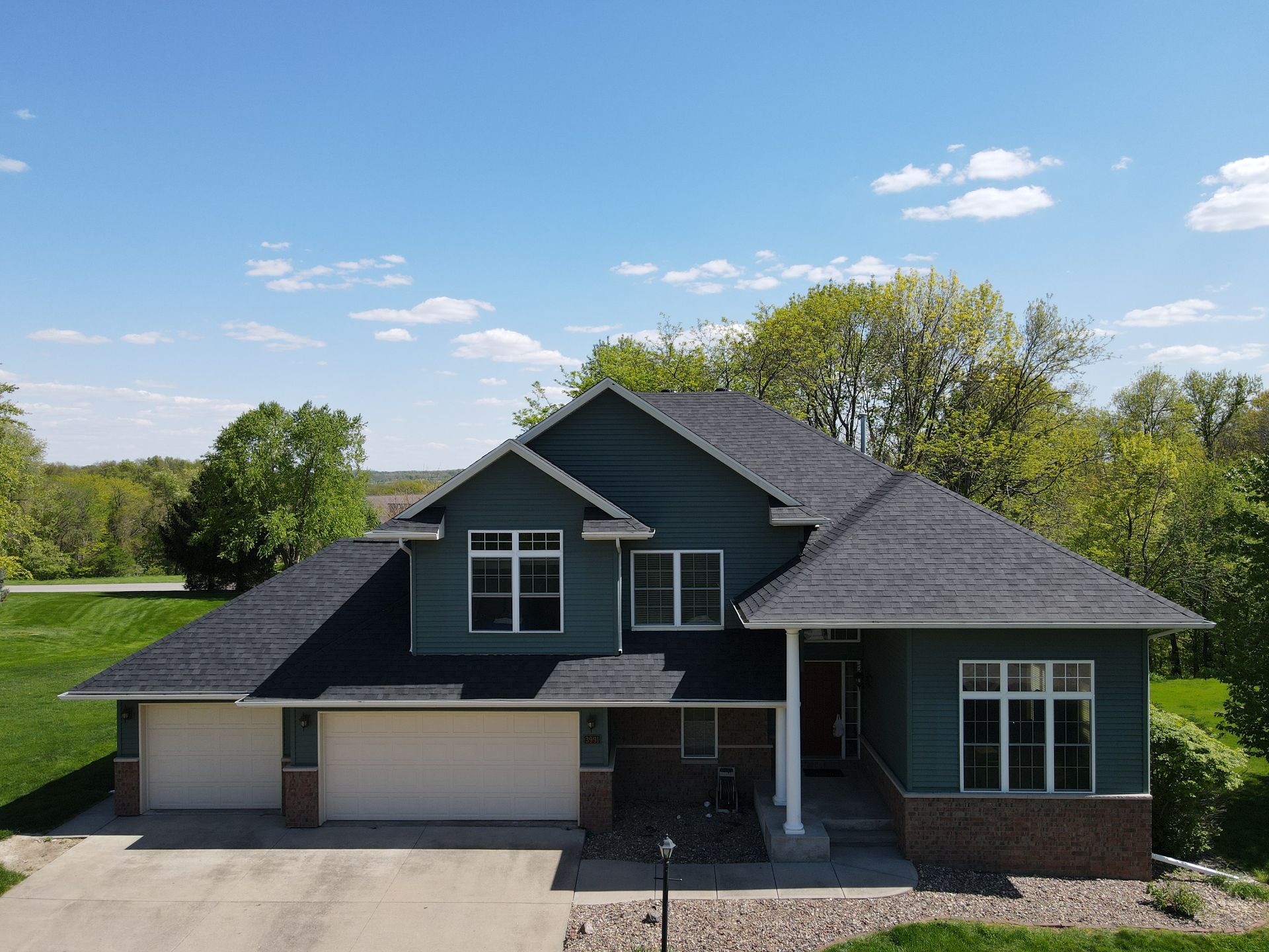 An aerial view of a large house with a black roof