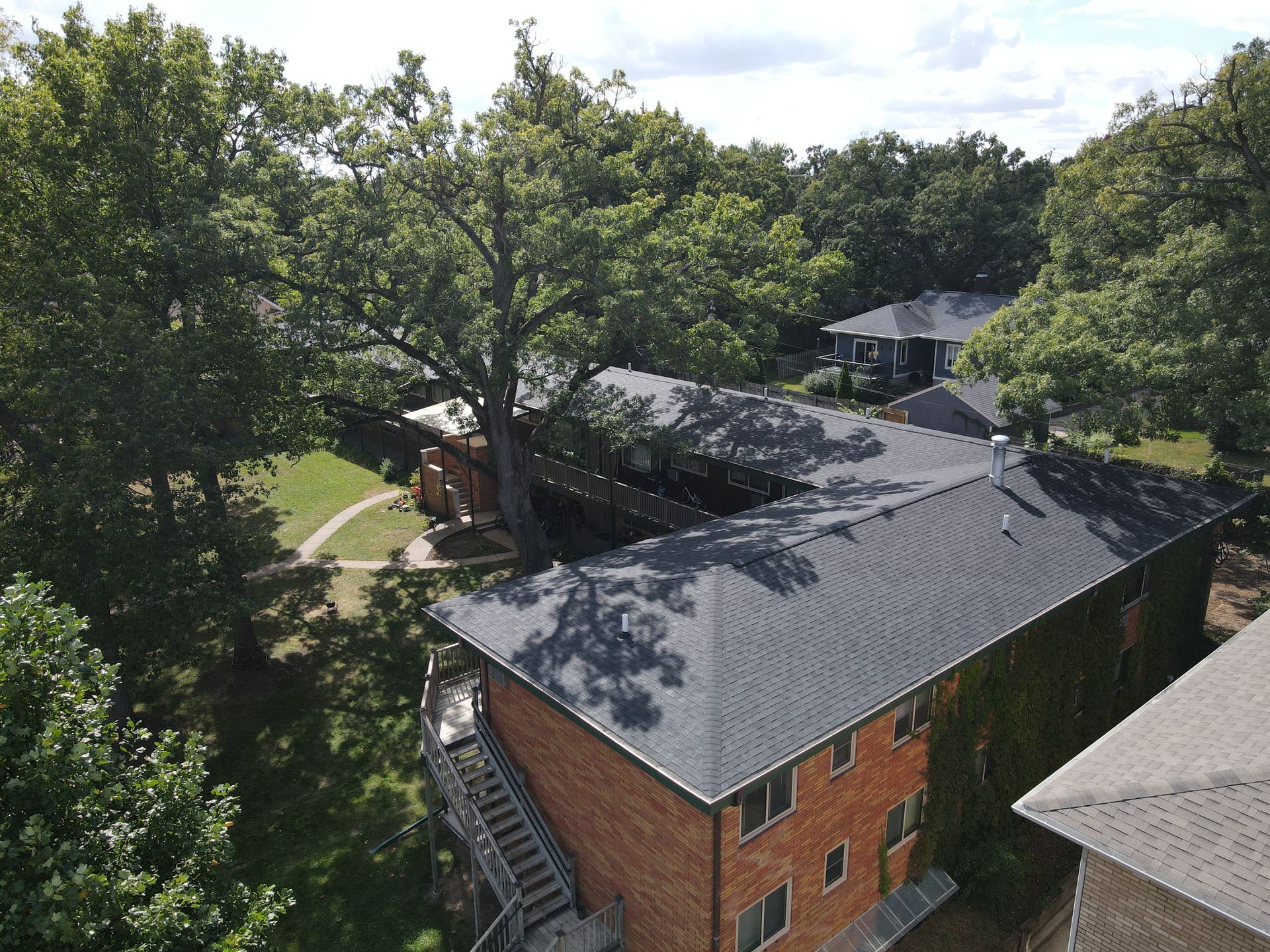 An aerial view of a brick apartment building surrounded by trees.