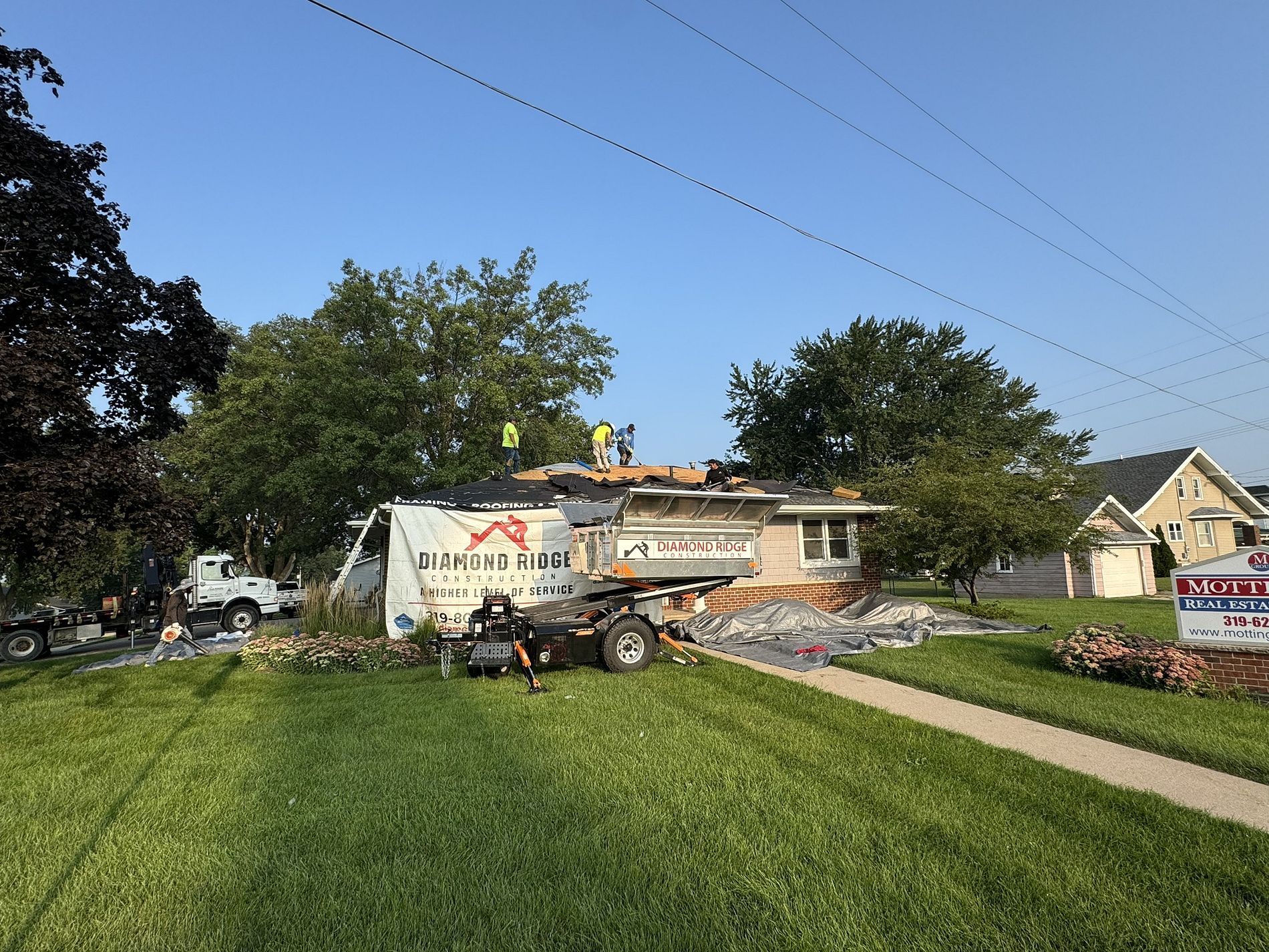 A group of people are working on the roof of a house.