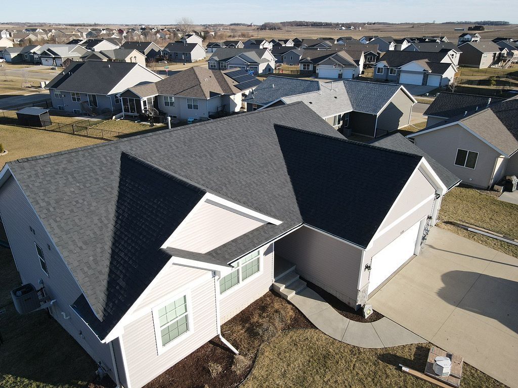 An aerial view of a house with a black roof in a residential area.