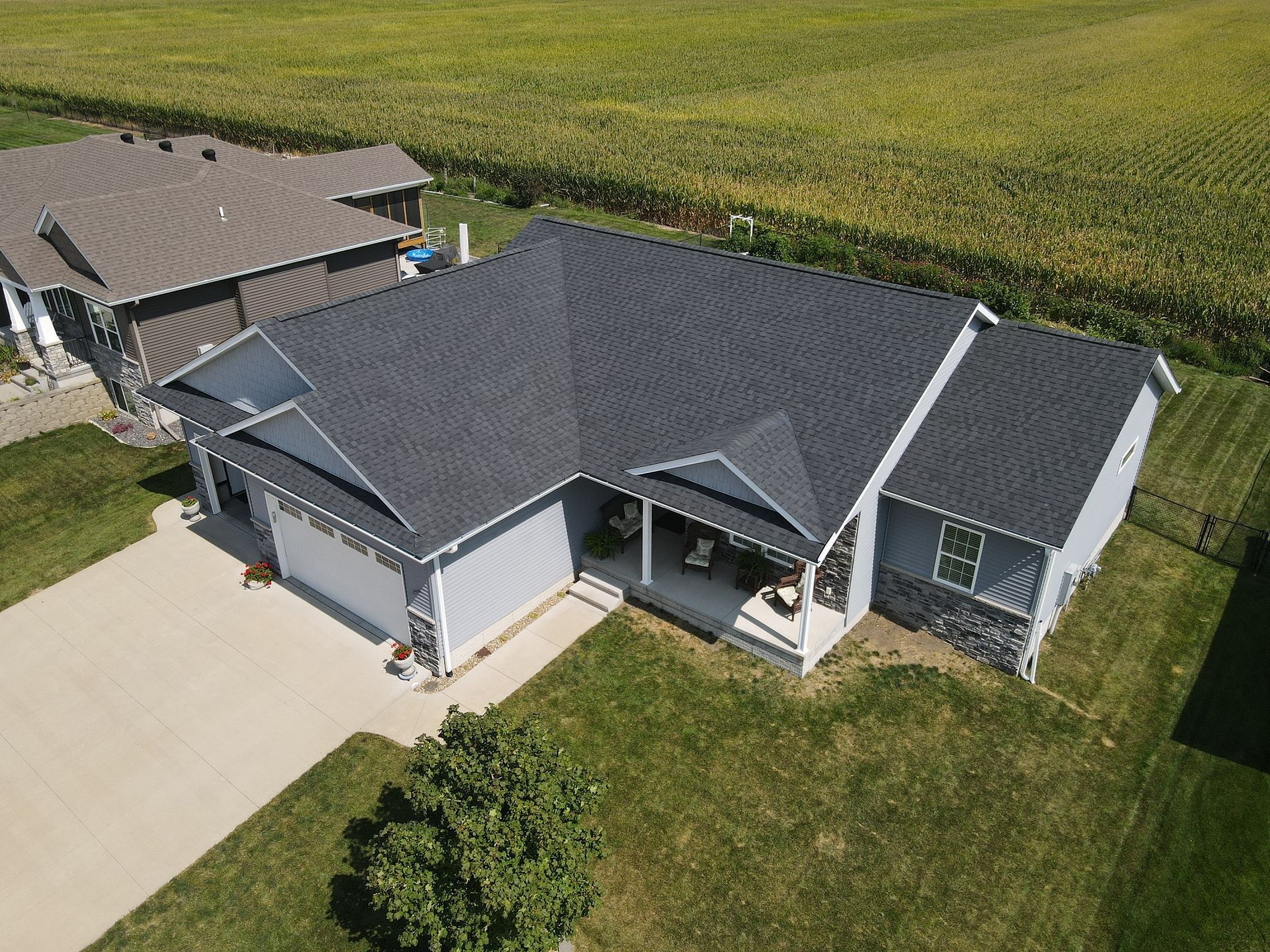 An aerial view of a house with a gray roof and a large driveway.