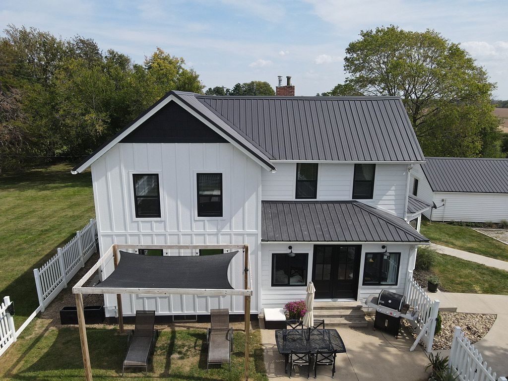 An aerial view of a white house with a black roof